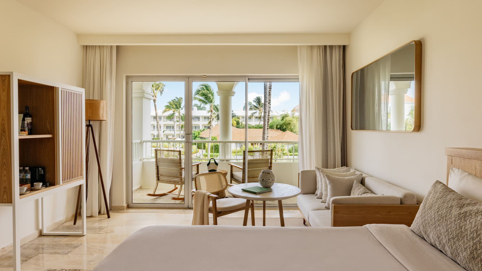 Hotel suite with private balcony, tropical palm trees, and modern decor.