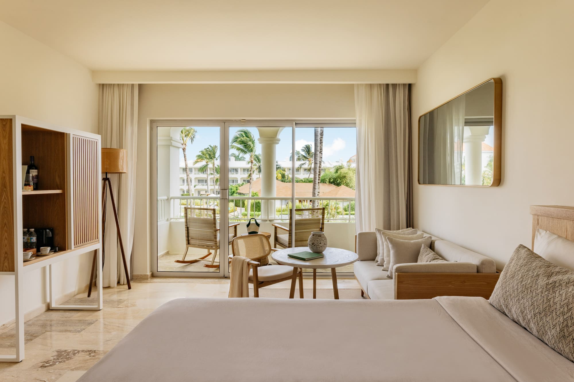 Hotel suite with private balcony, tropical palm trees, and modern decor.