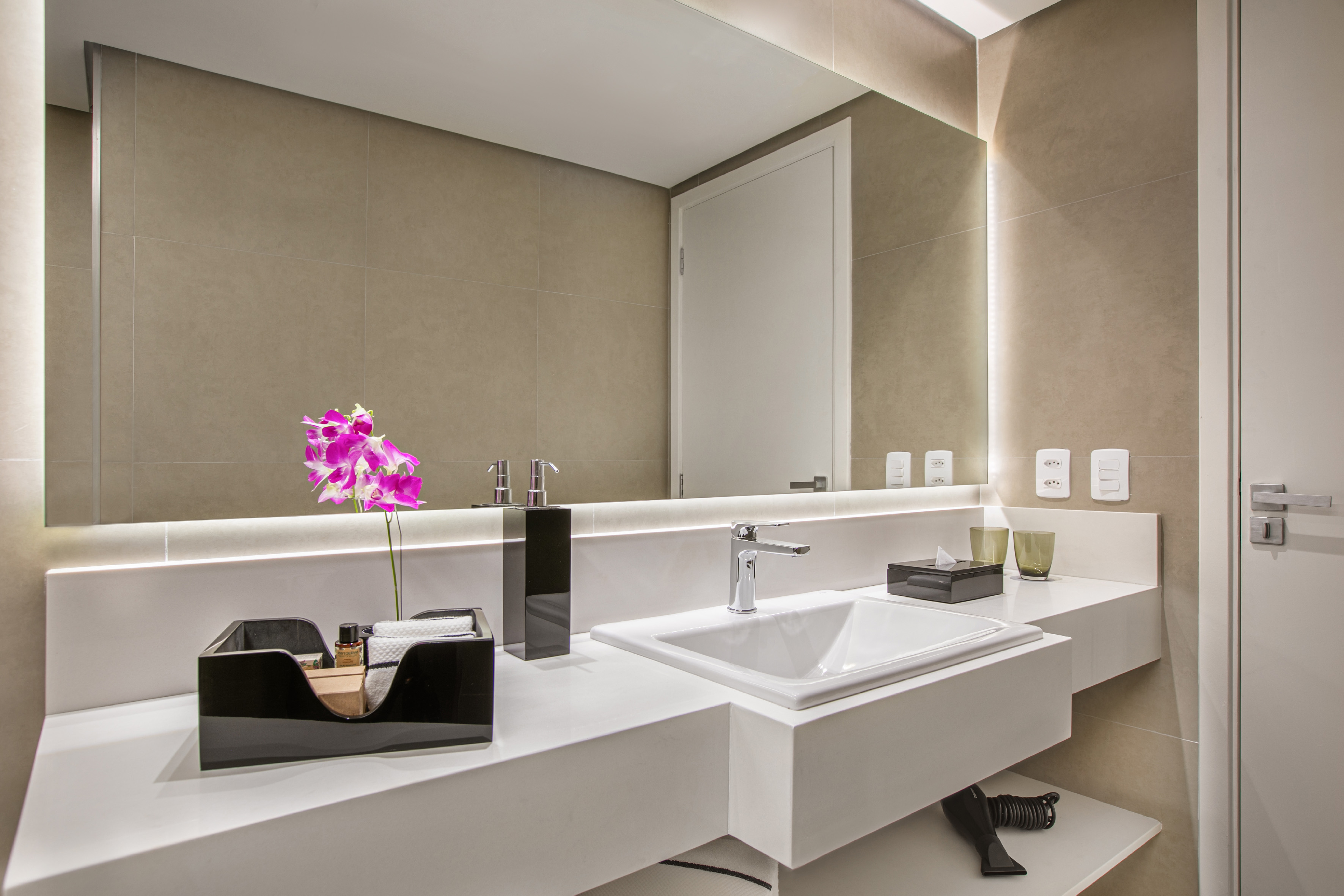 Modern bathroom vanity with integrated sink, backlit mirror, and pink orchid.
