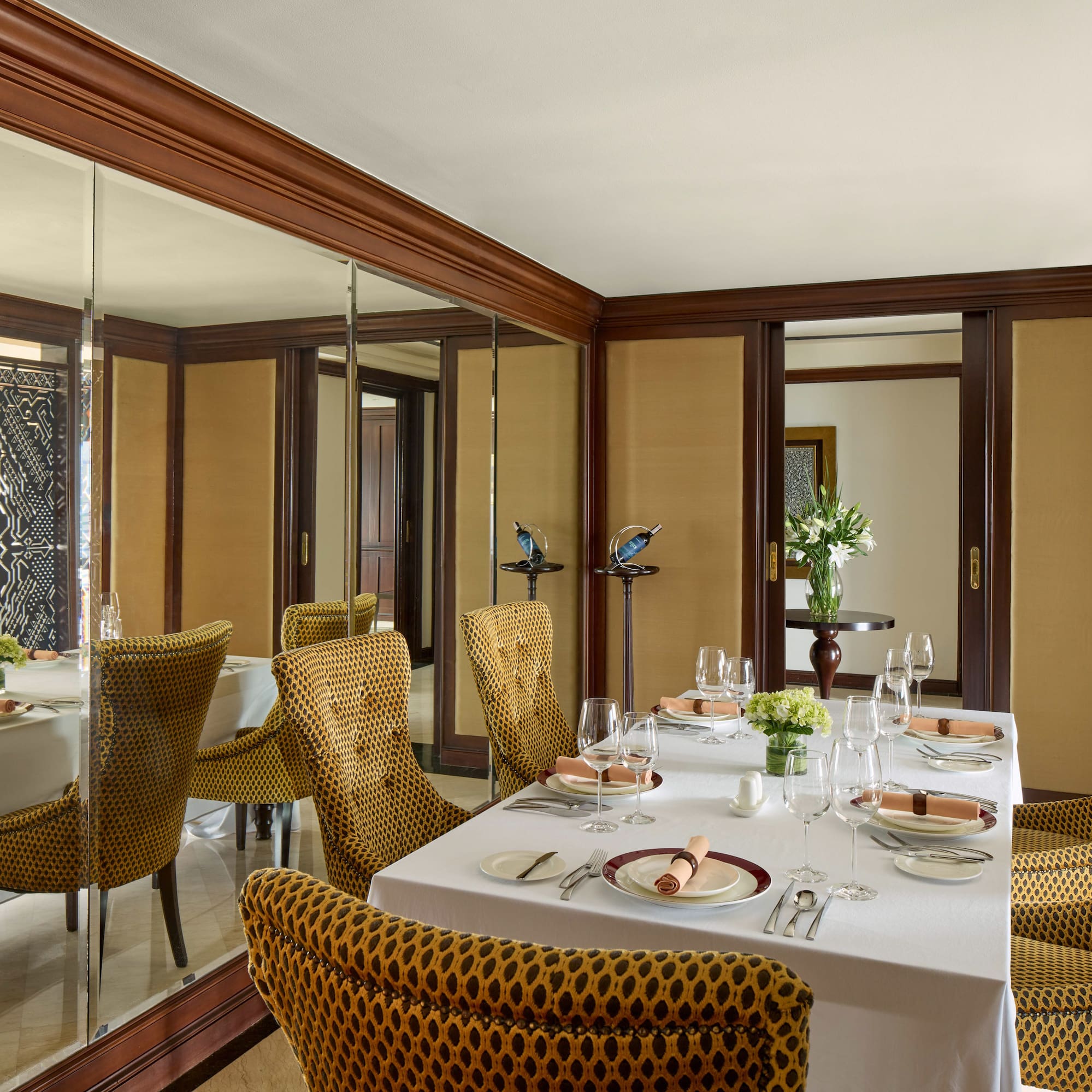 a dining room with a mirror wall and a table set with plates and glasses