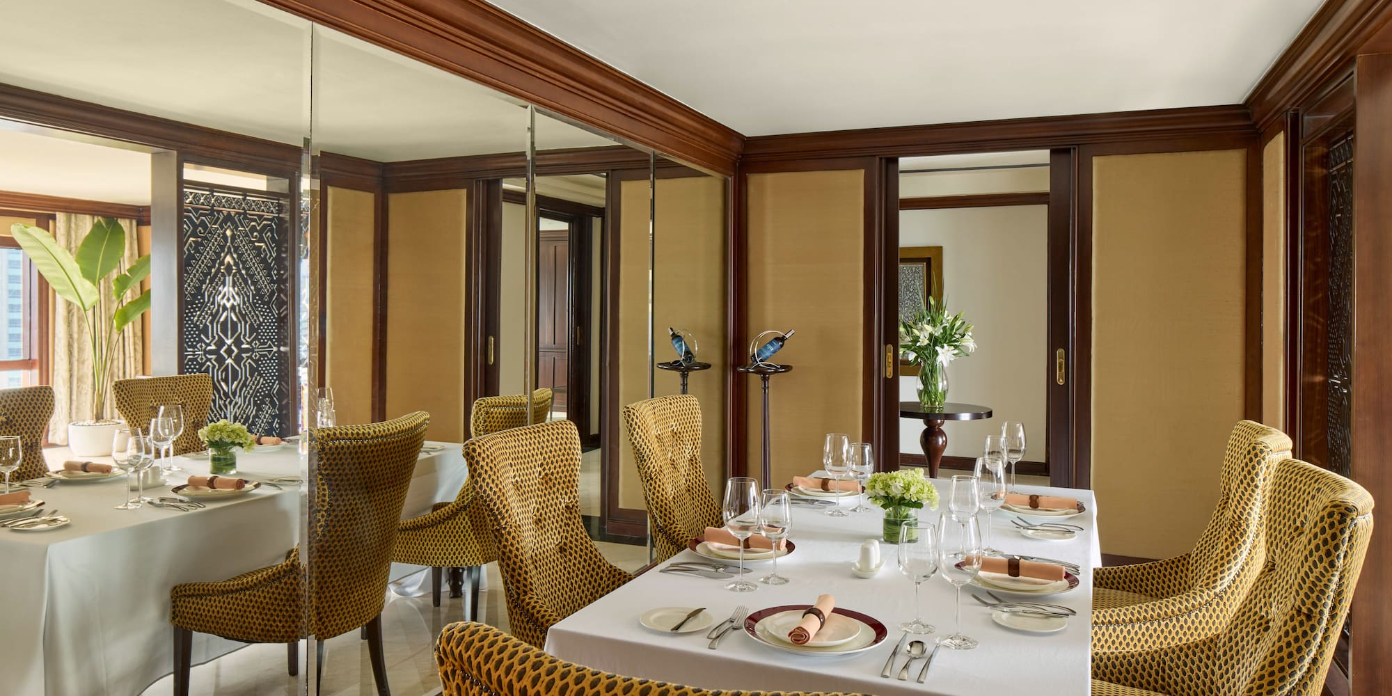 a dining room with a mirror wall and a table set with plates and glasses