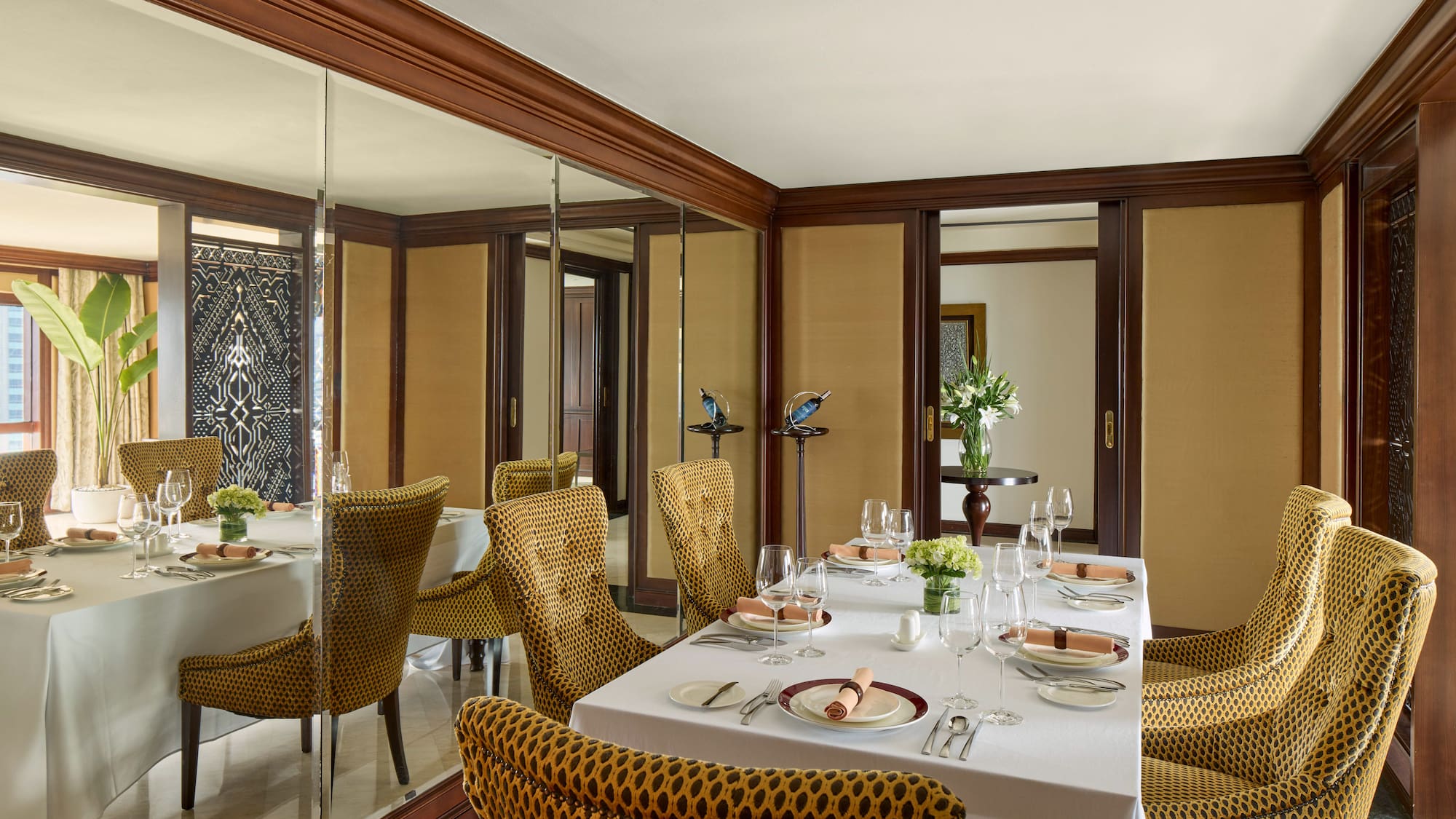 a dining room with a mirror wall and a table set with plates and glasses