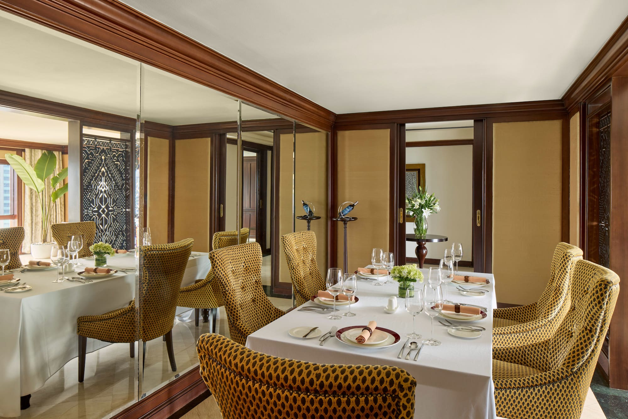 a dining room with a mirror wall and a table set with plates and glasses