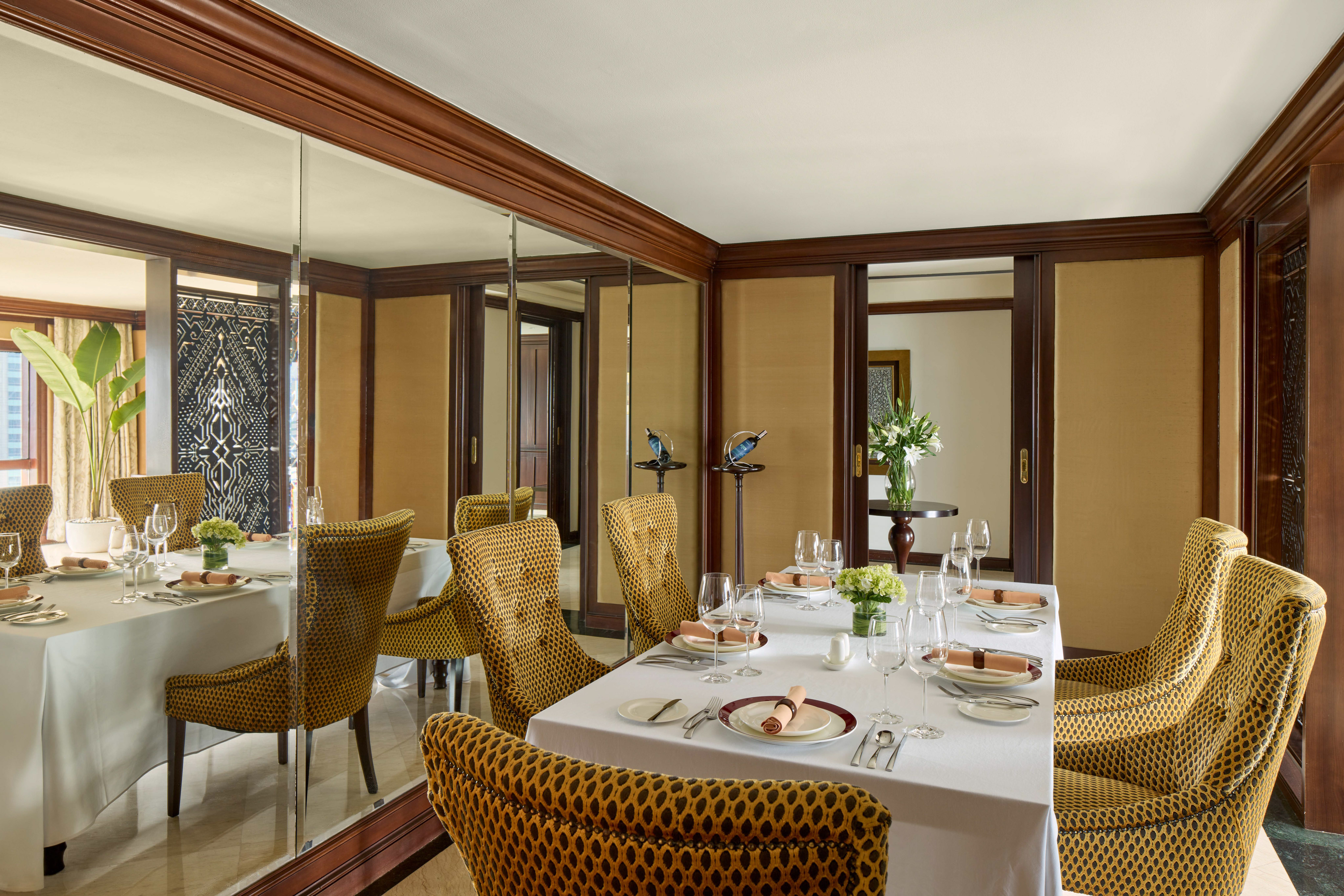 a dining room with a mirror wall and a table set with plates and glasses