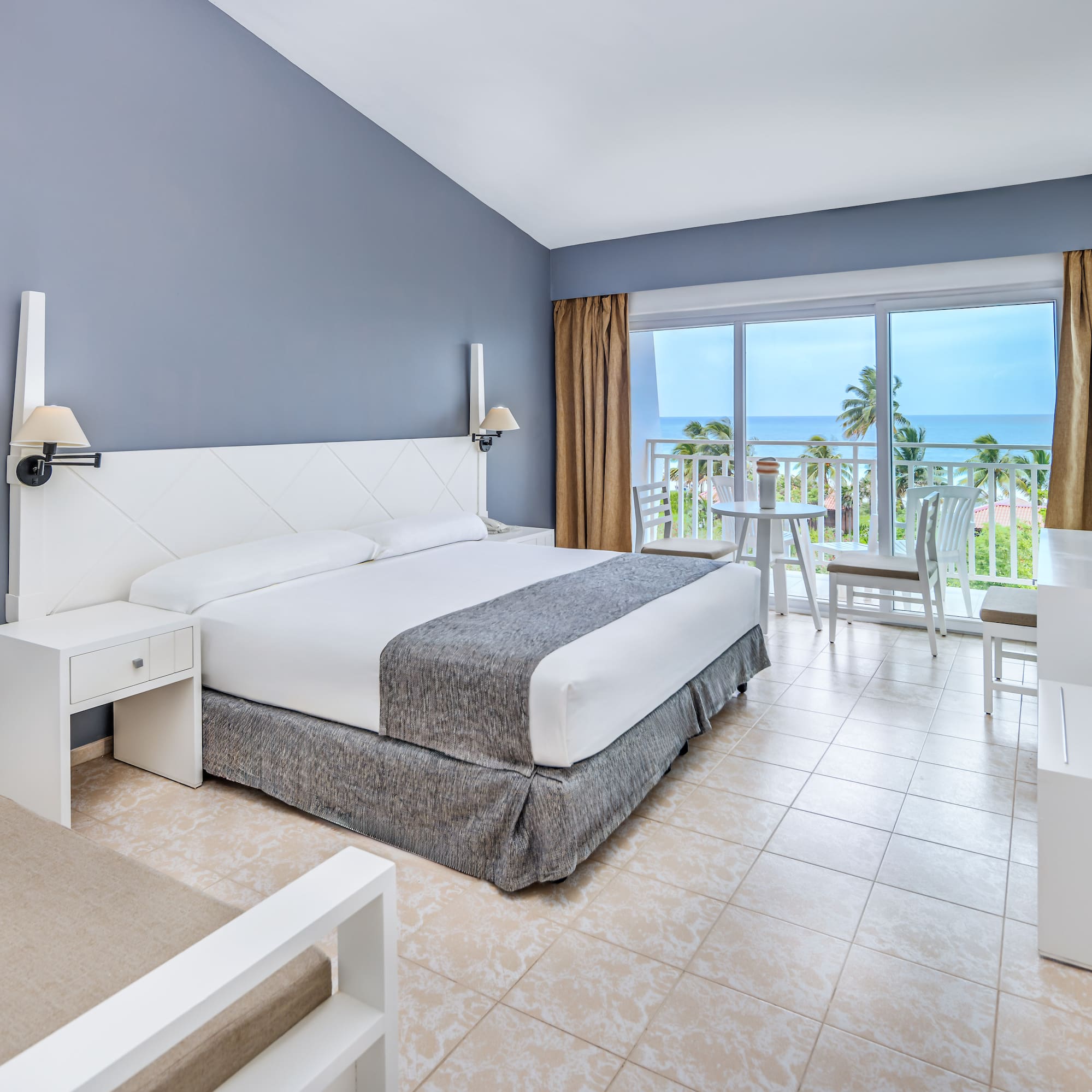 a bedroom with a table and chairs and a balcony overlooking the ocean