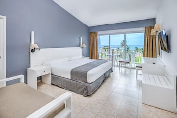 a bedroom with a table and chairs and a balcony overlooking the ocean