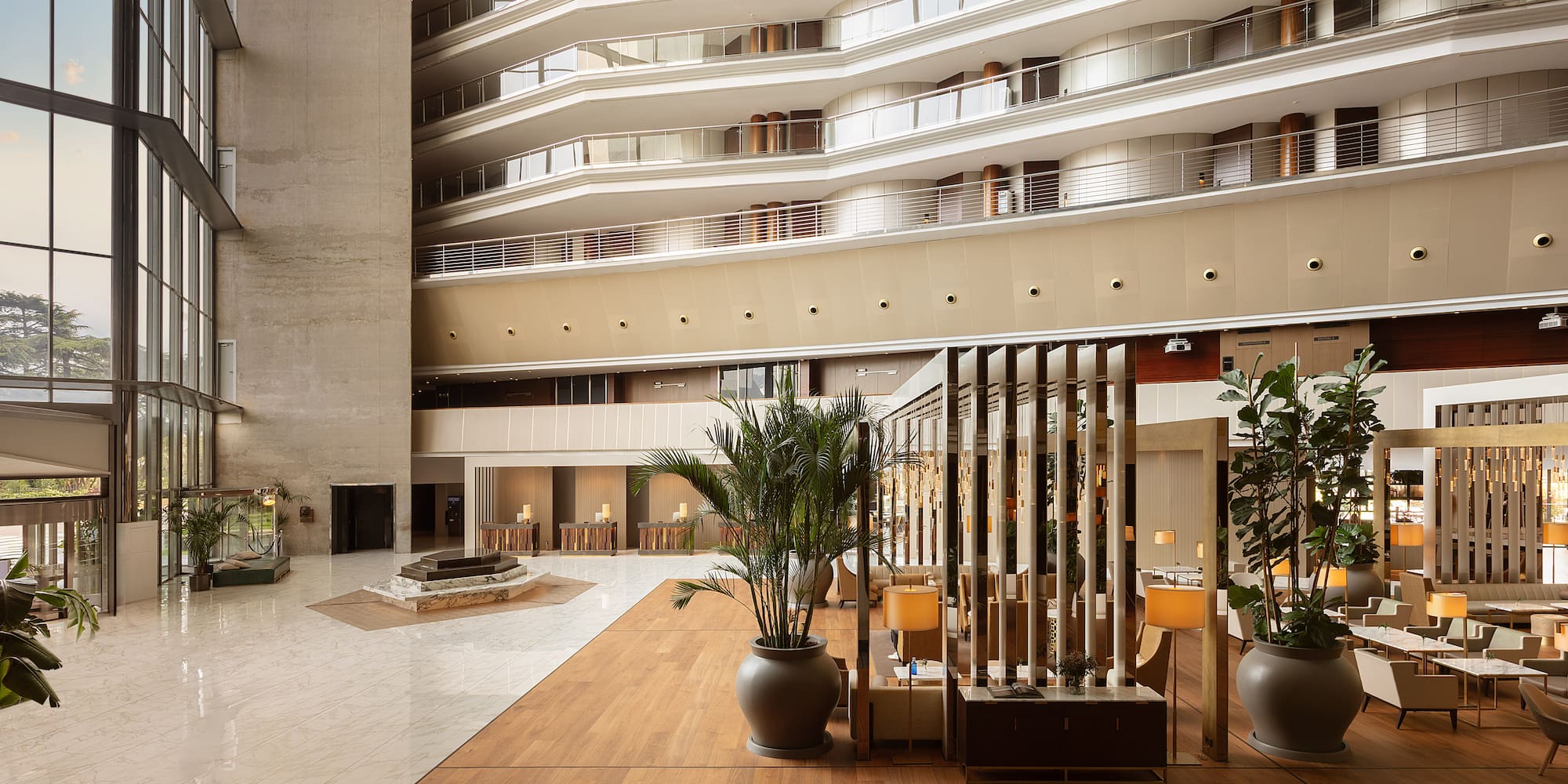 Spacious modern hotel lobby with multi-story atrium, large windows, and seating. - Torre Melina Gran Meliá, Barcelona