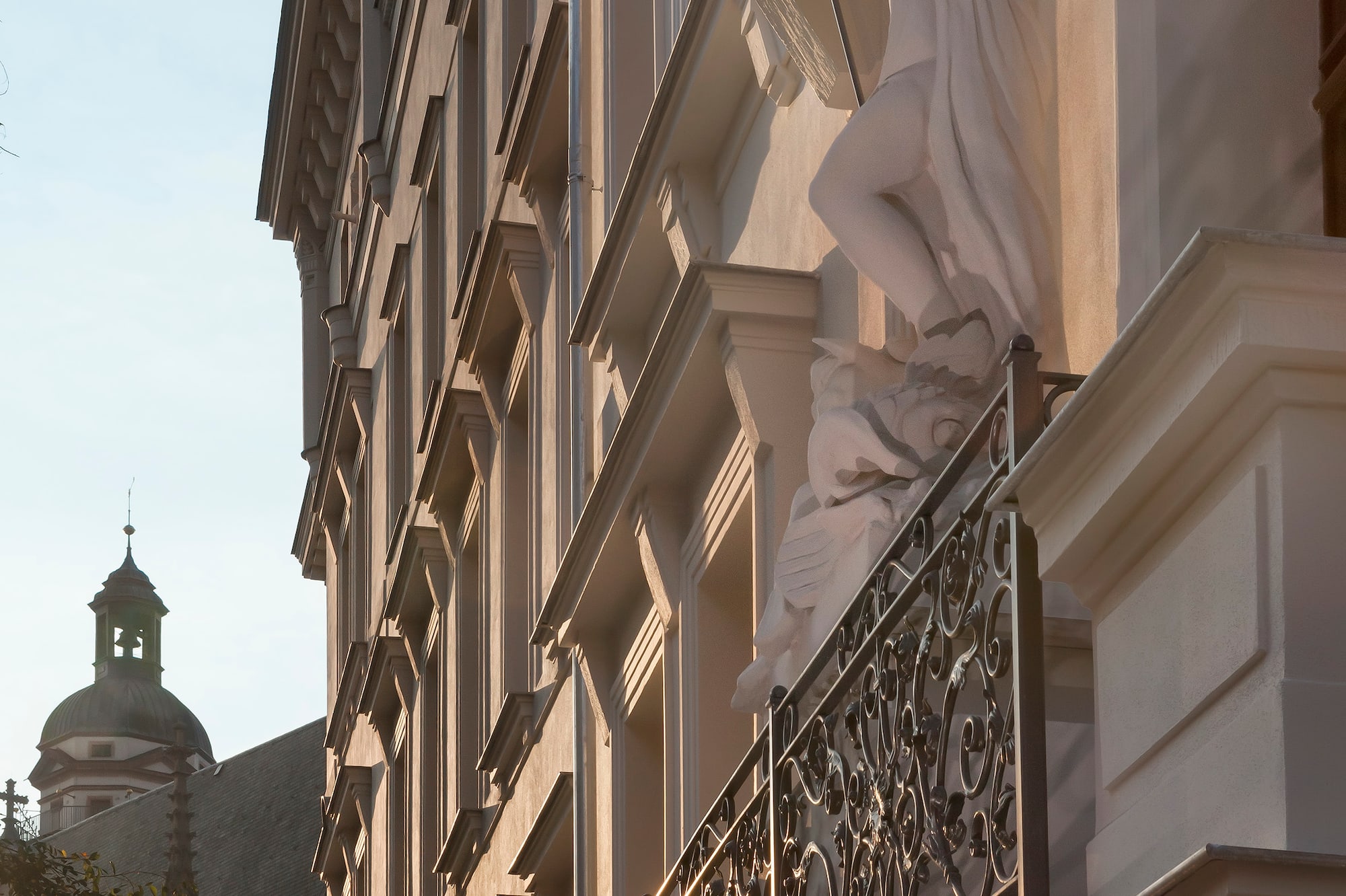 Historic building facade, bearded statue on ornate balcony, church spire.