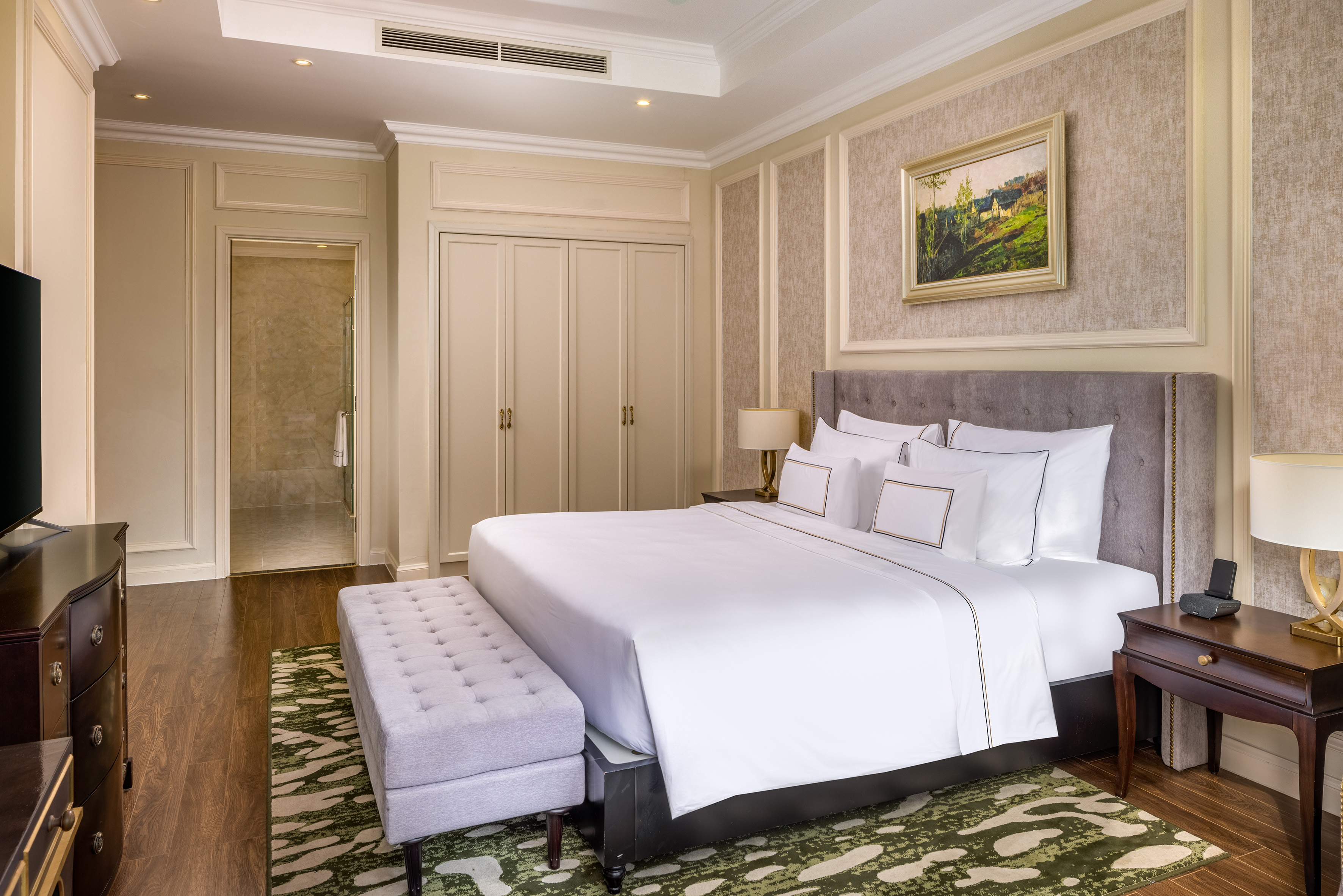 Luxury hotel bedroom with king-size bed, upholstered headboard, and elegant decor.