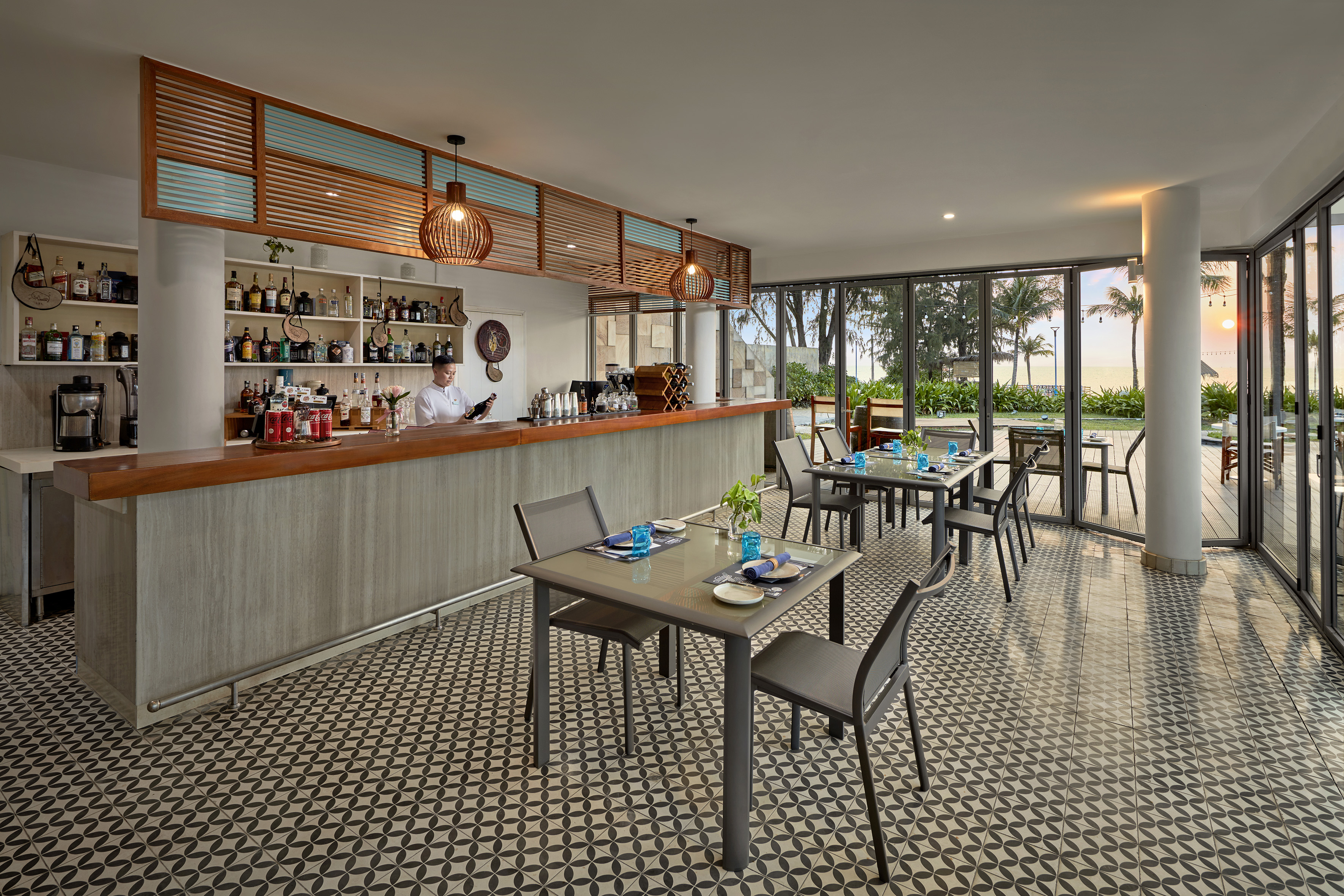 Beachfront hotel bar and restaurant with a bartender and ocean views.
