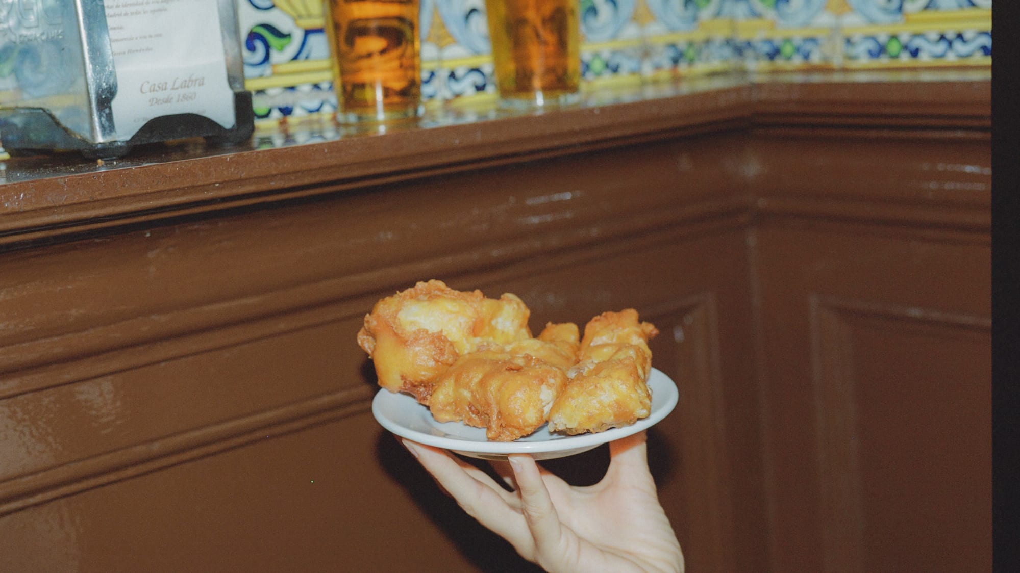 a hand holding a plate of fried food