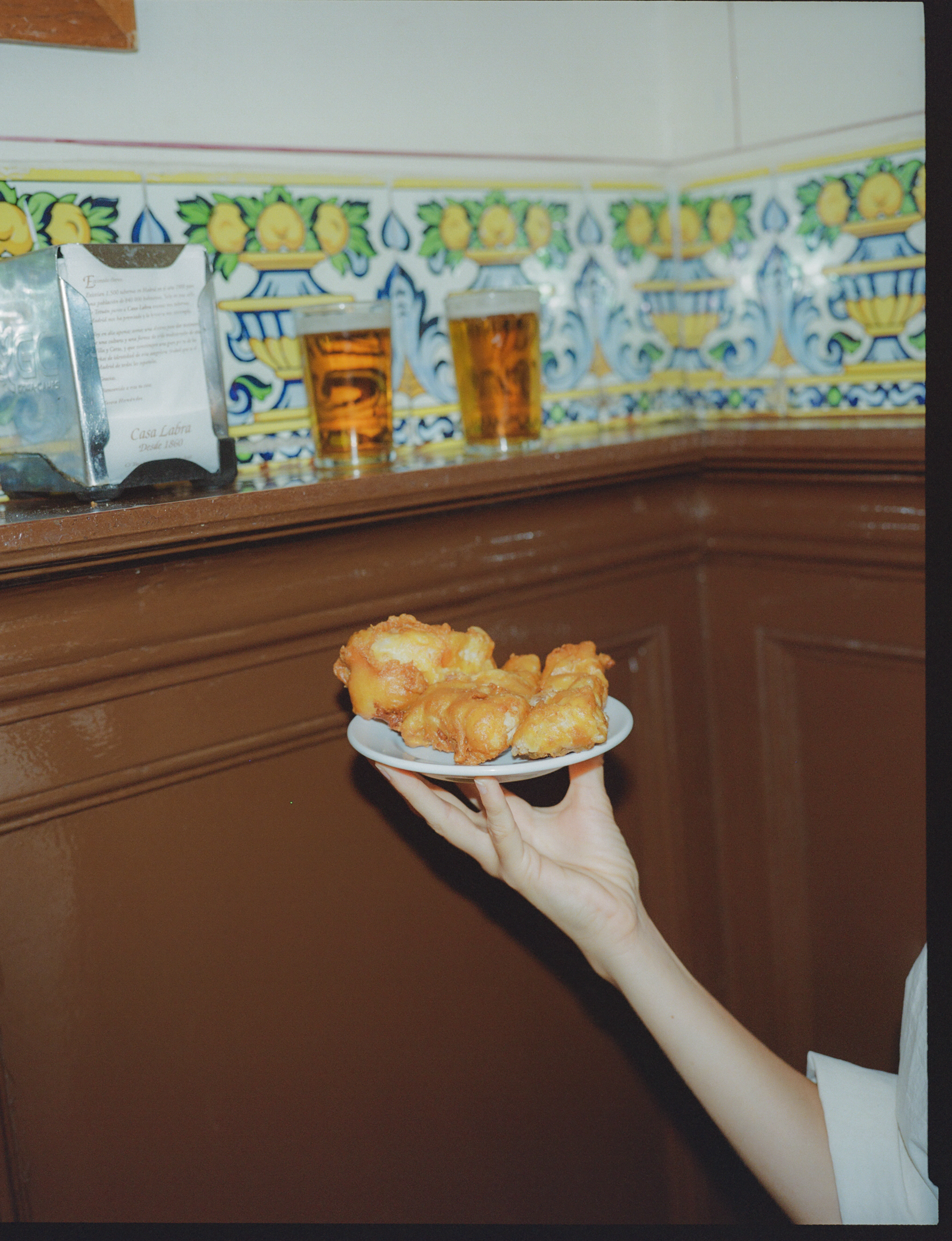 a hand holding a plate of fried food