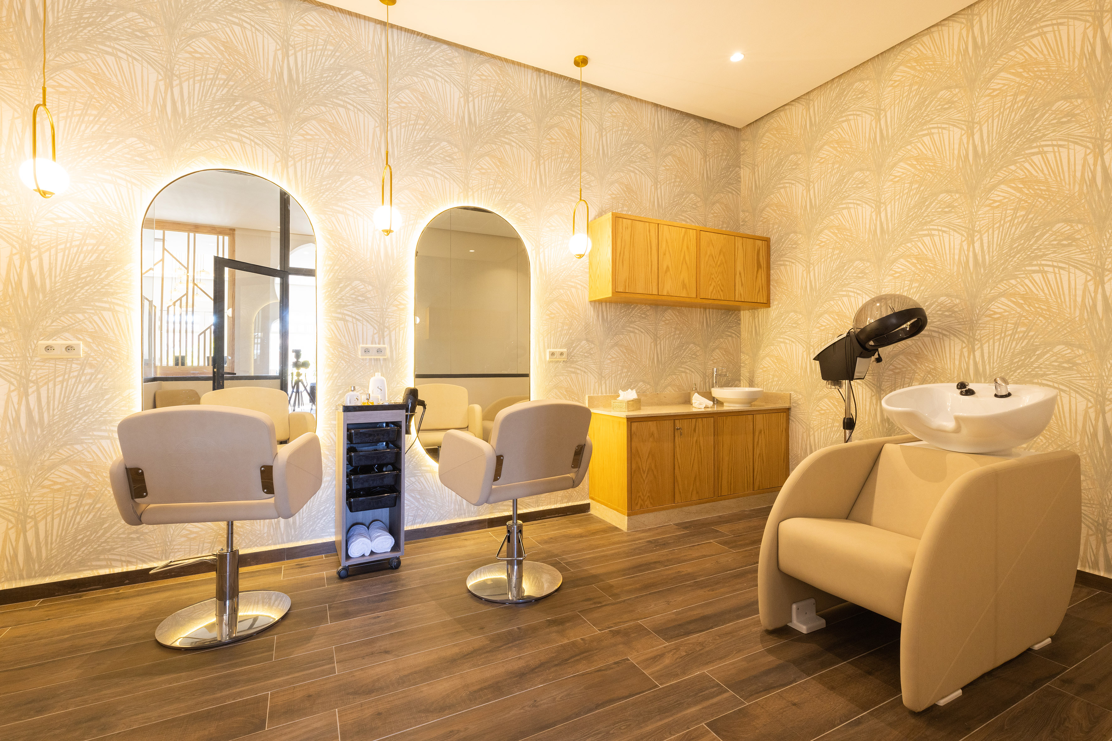 Modern hair salon with two styling chairs, lighted mirrors, and wash station.