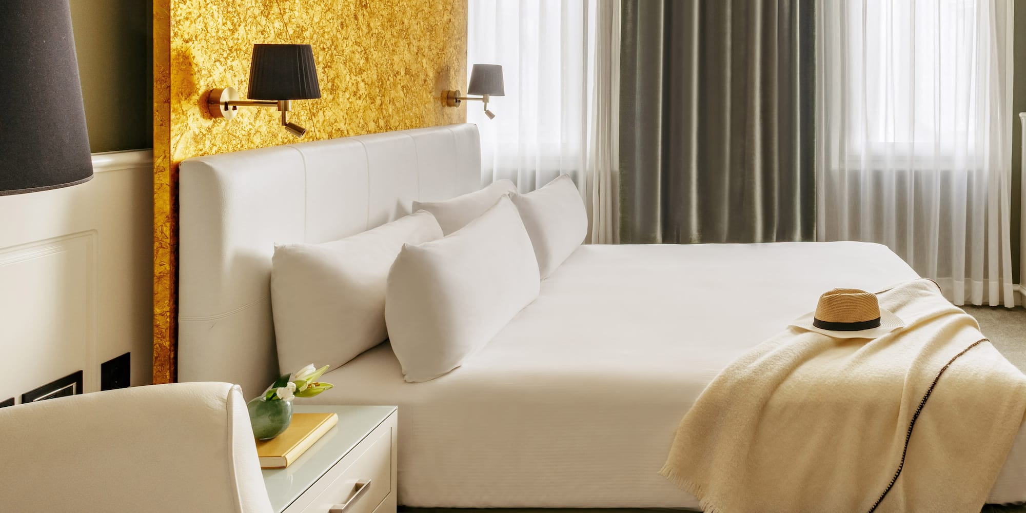 a bed with a hat and a table in front of a window