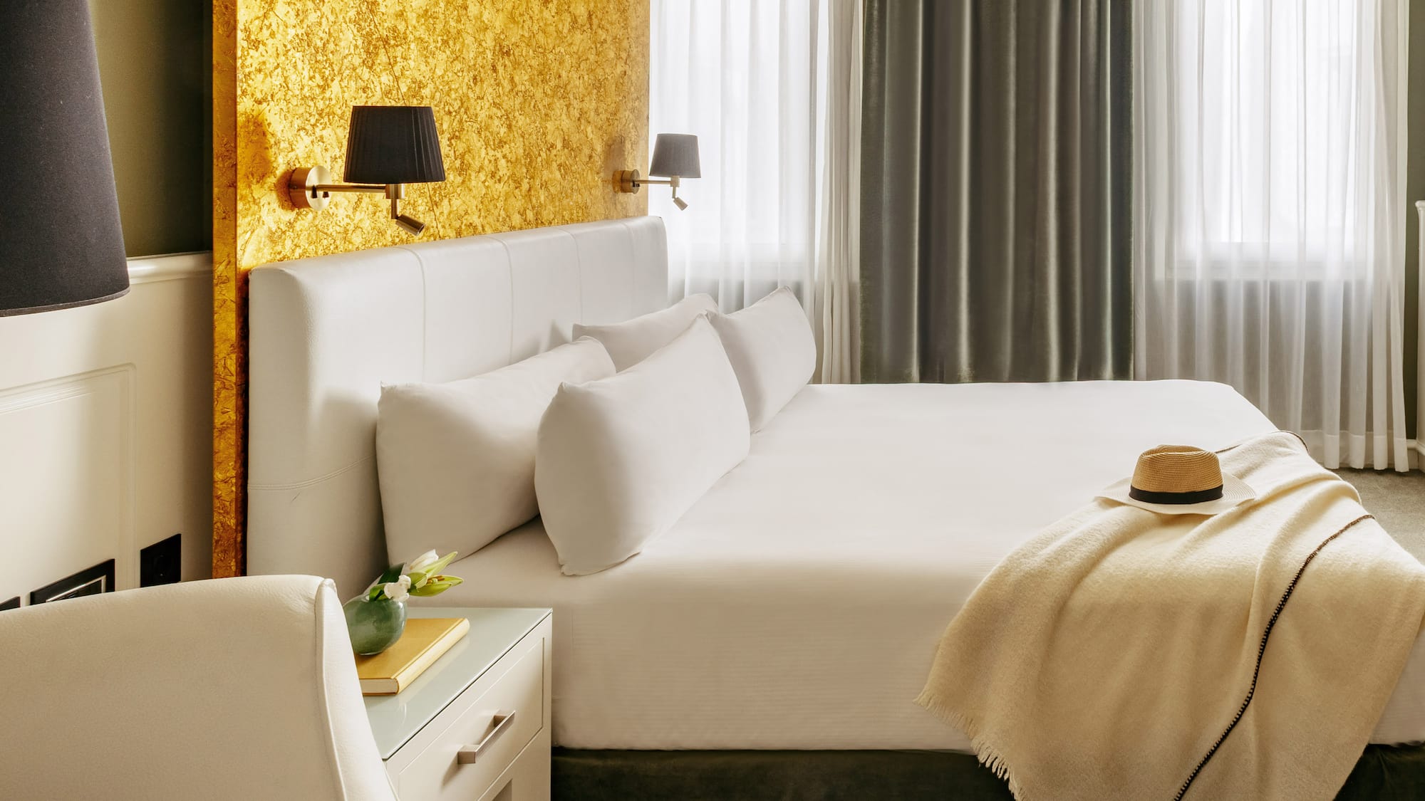 a bed with a hat and a table in front of a window