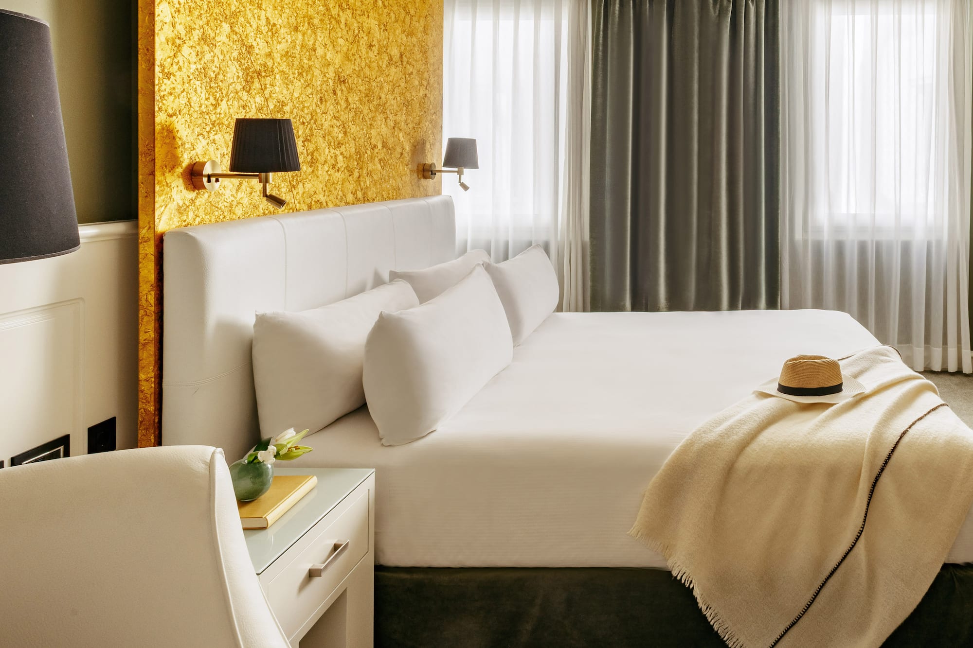 a bed with a hat and a table in front of a window