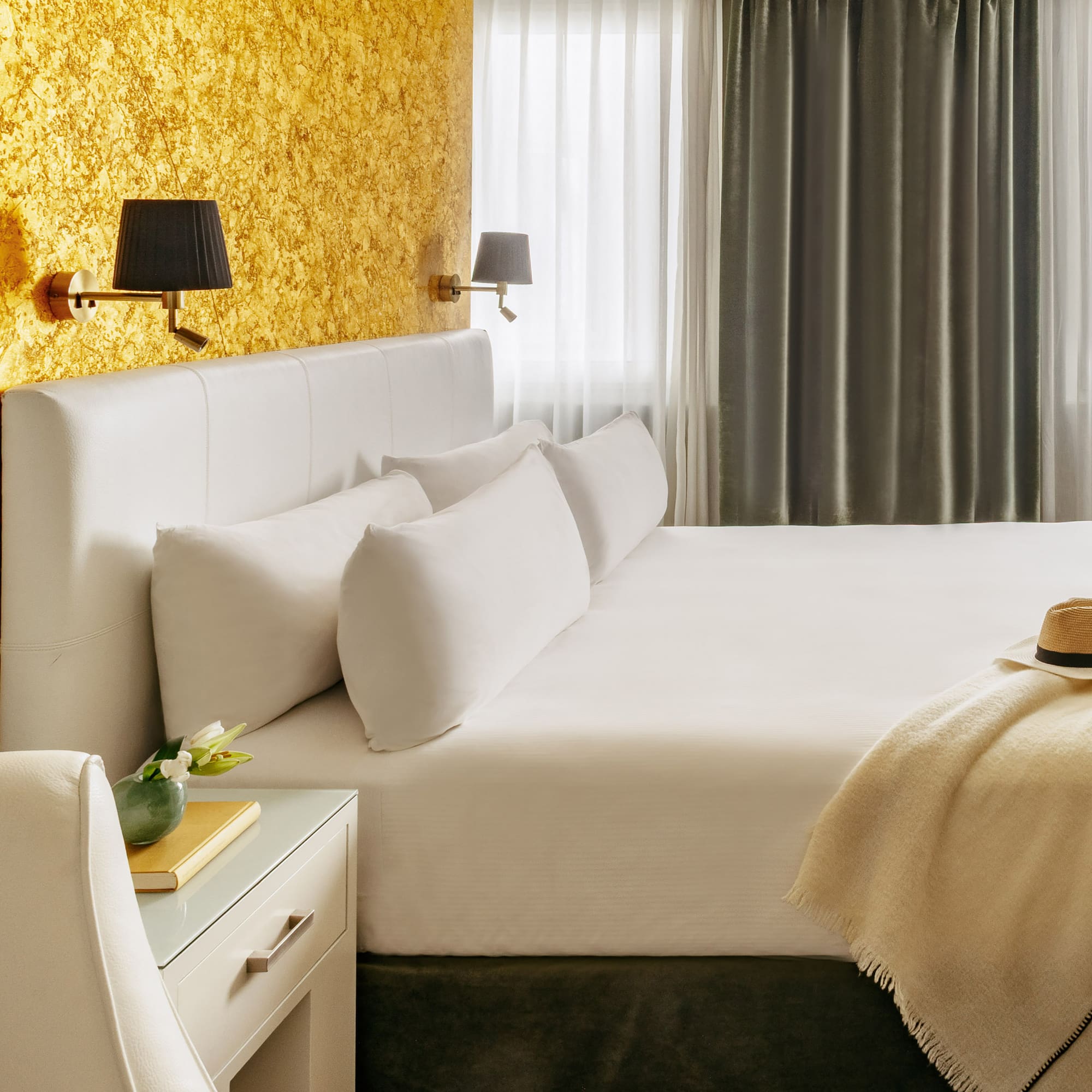 a bed with a hat and a table in front of a window