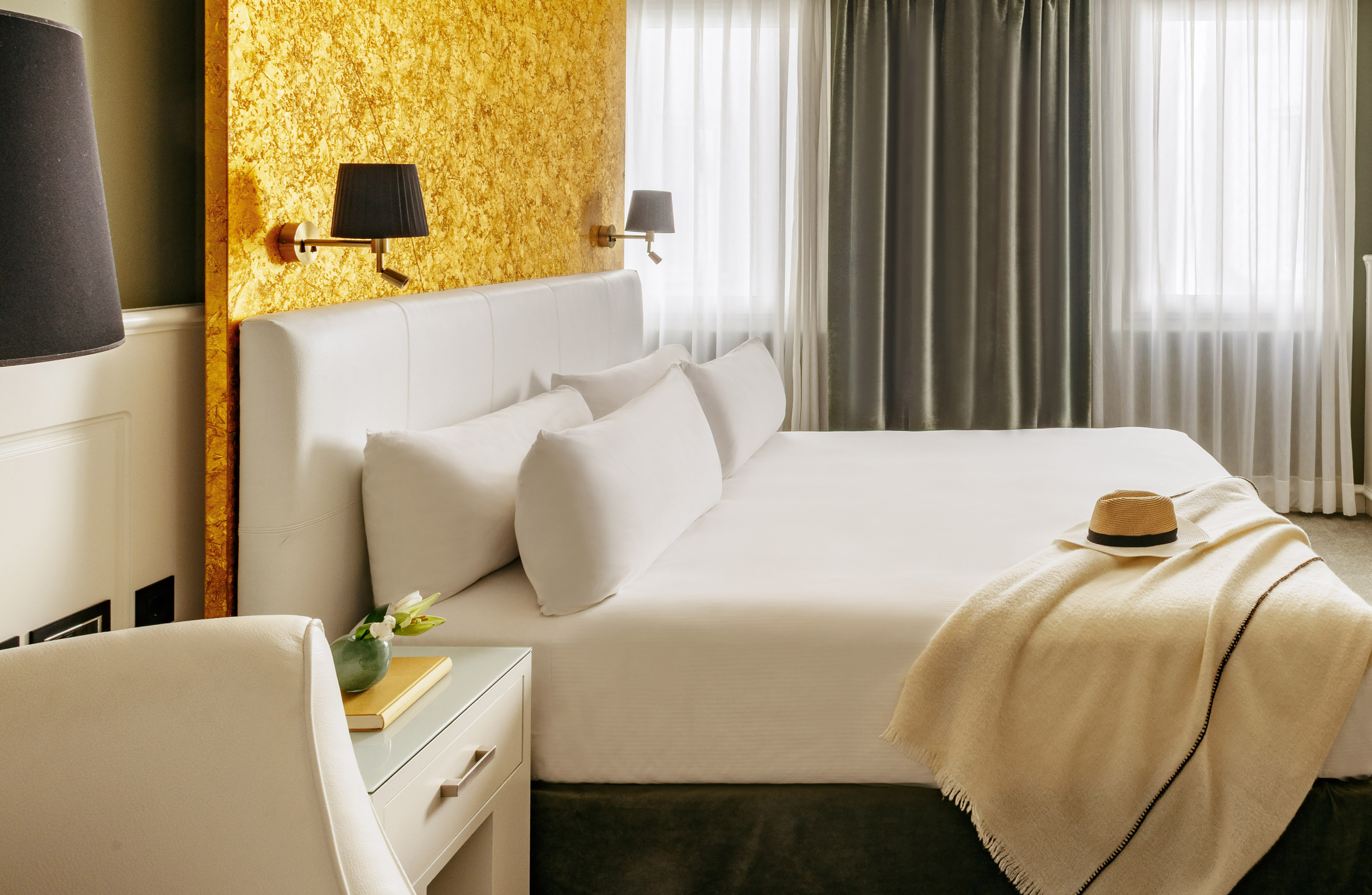 a bed with a hat and a table in front of a window