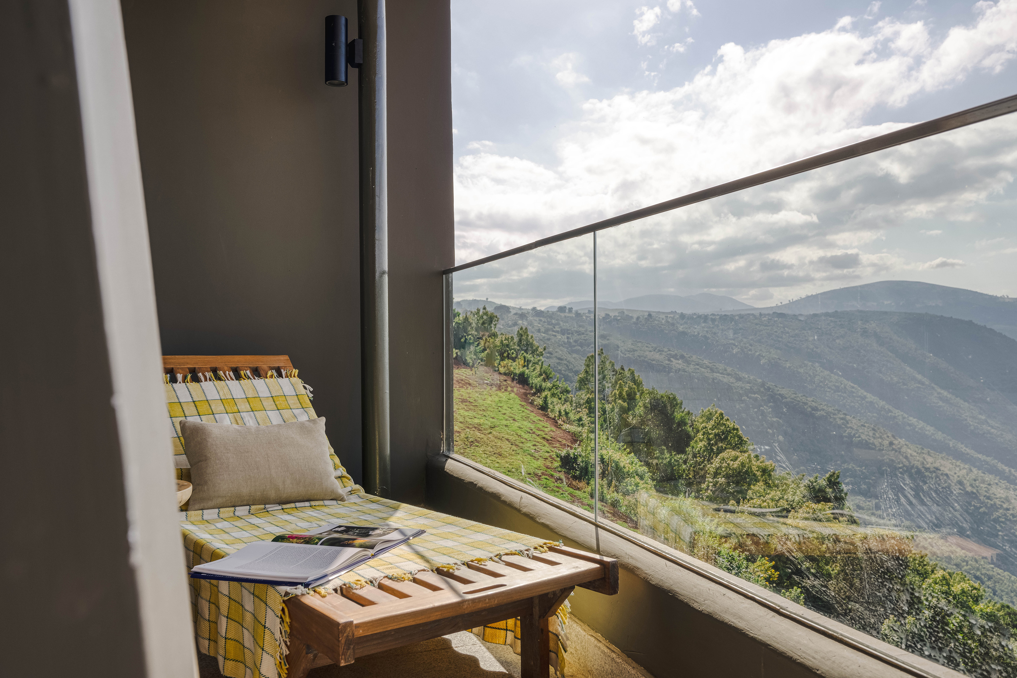 Outdoor balcony with lounge chair, book, and panoramic mountain view.
