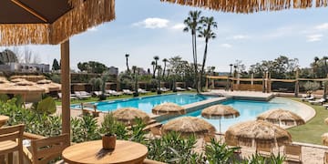 a pool with straw umbrellas and tables
