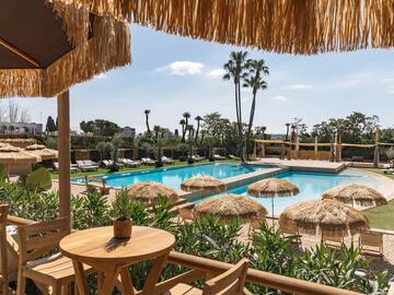 a pool with straw umbrellas and tables