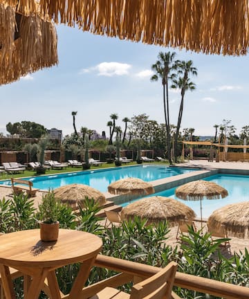a pool with straw umbrellas and tables