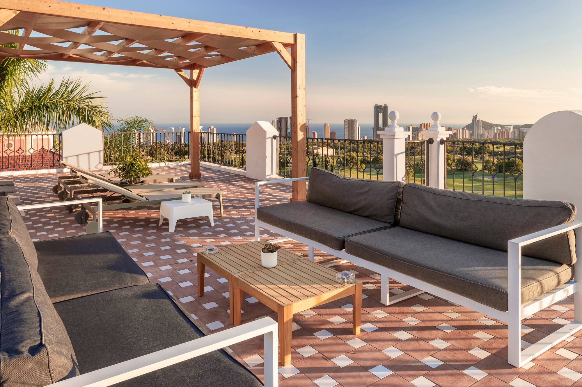 Rooftop terrace, wooden pergola, outdoor sofas, city skyline, and sea view.