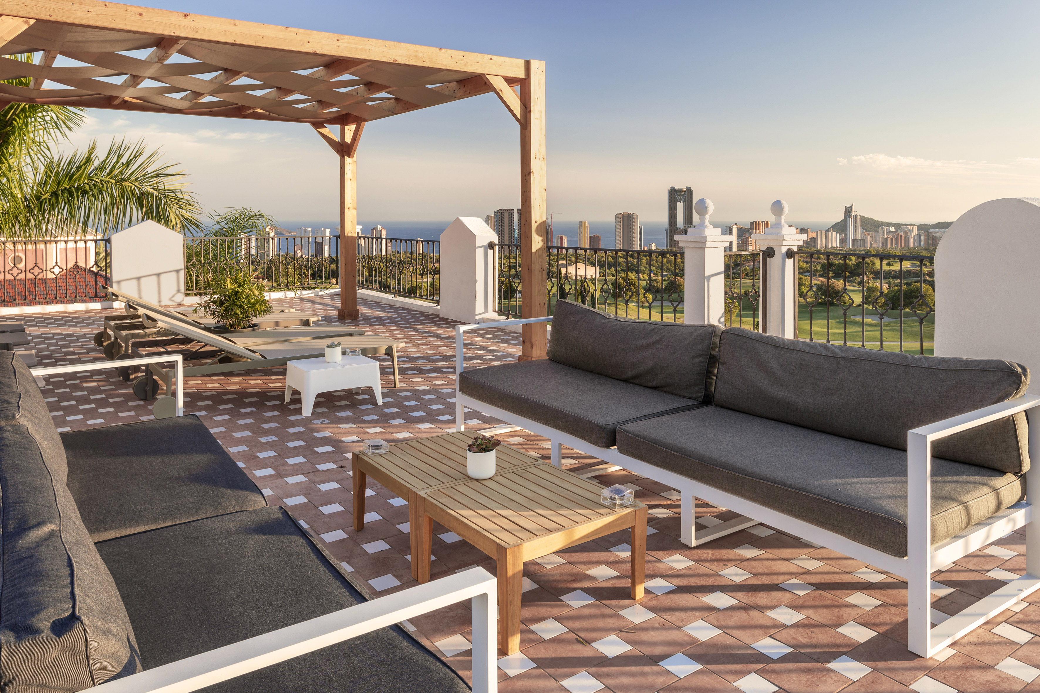 Rooftop terrace, wooden pergola, outdoor sofas, city skyline, and sea view.