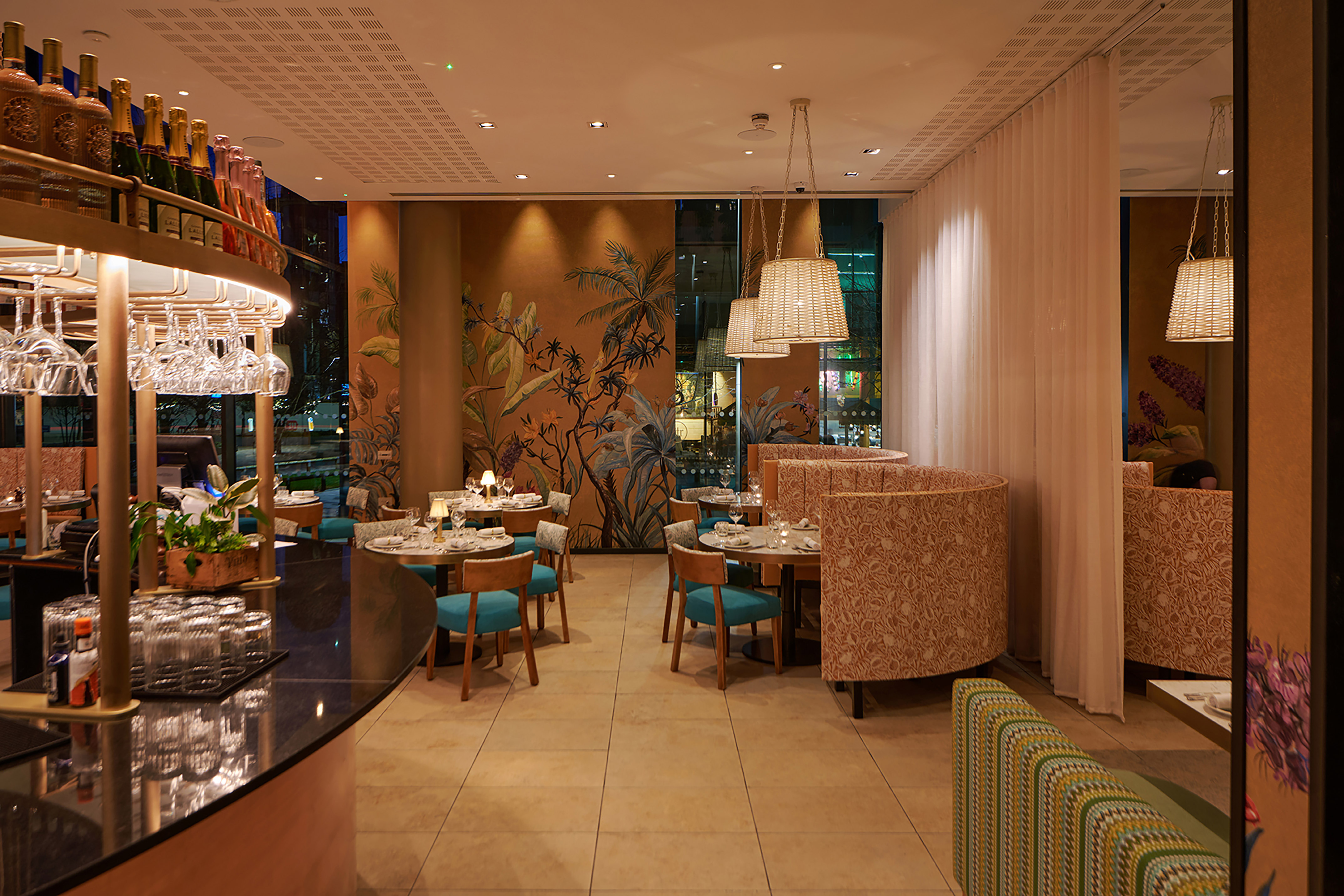 Modern restaurant interior with bar, elegant dining tables, and tropical wall mural.