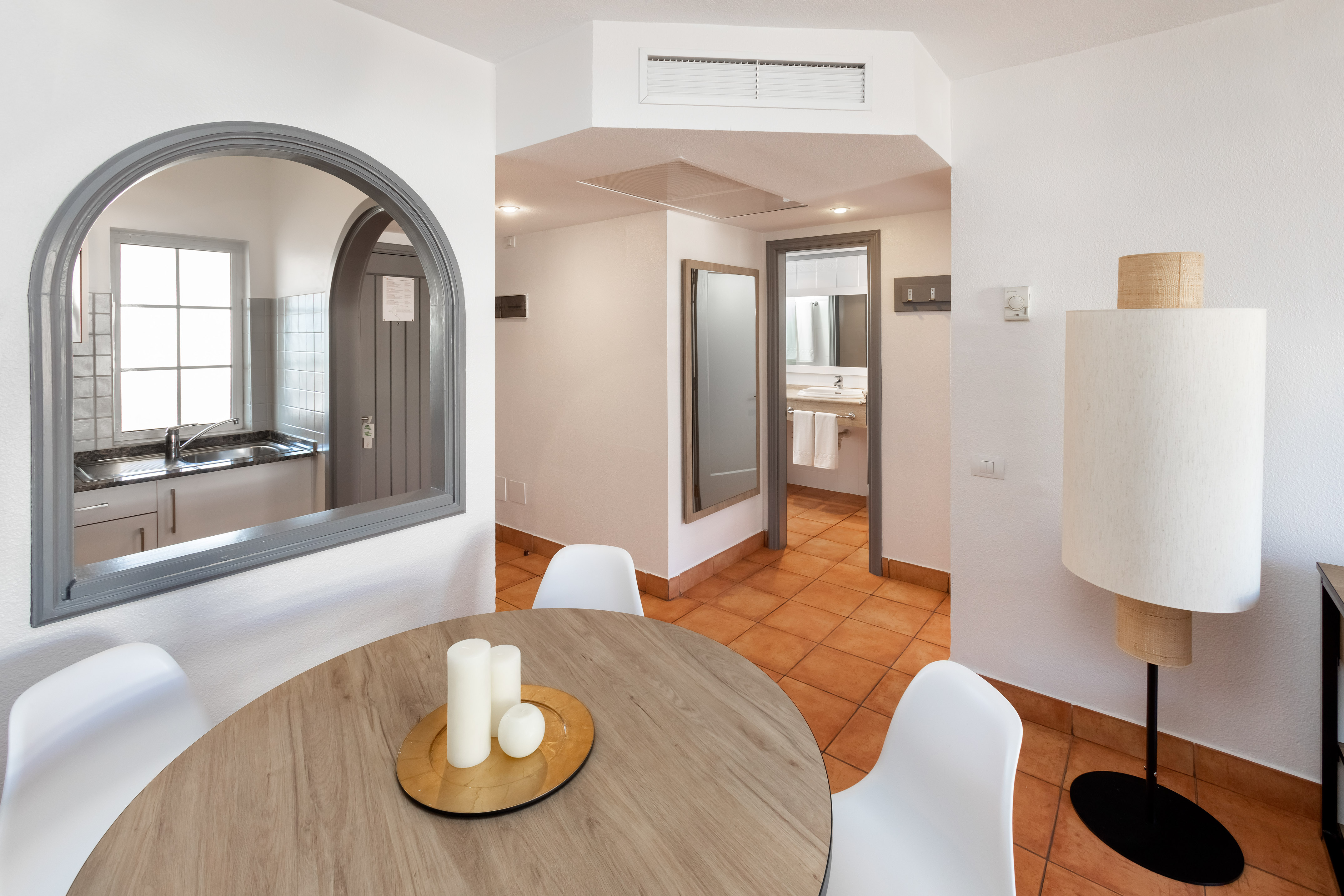 Modern studio apartment with dining table, kitchen view, and bathroom.