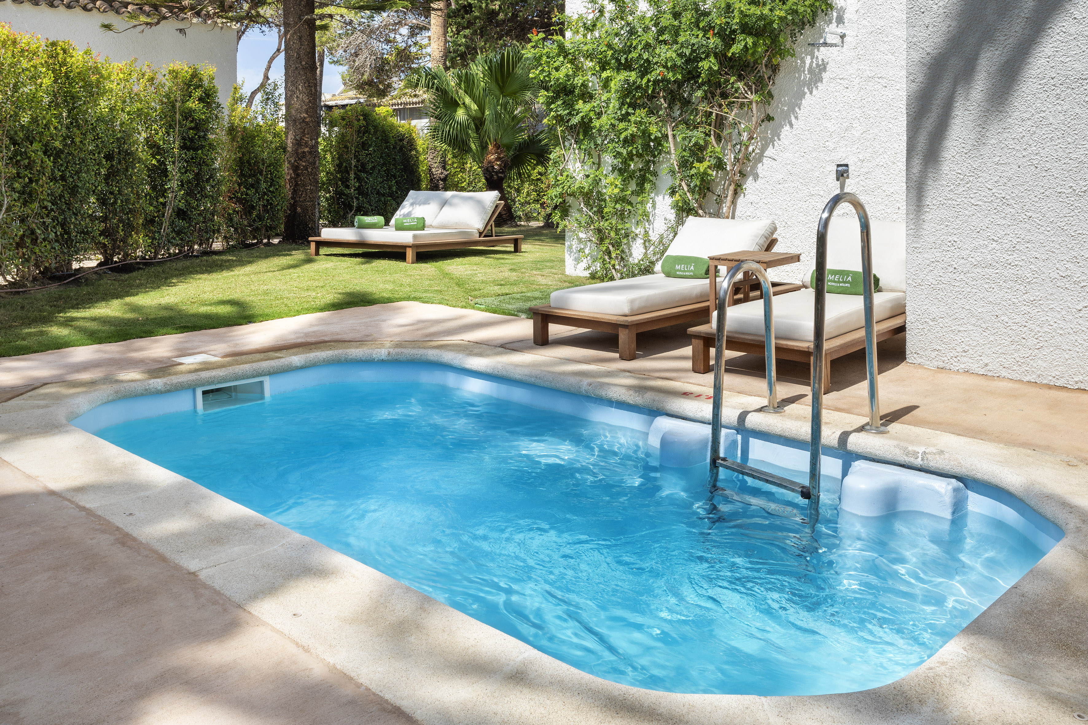 Private plunge pool with sun loungers in a sunny garden at Meliá Hotels.