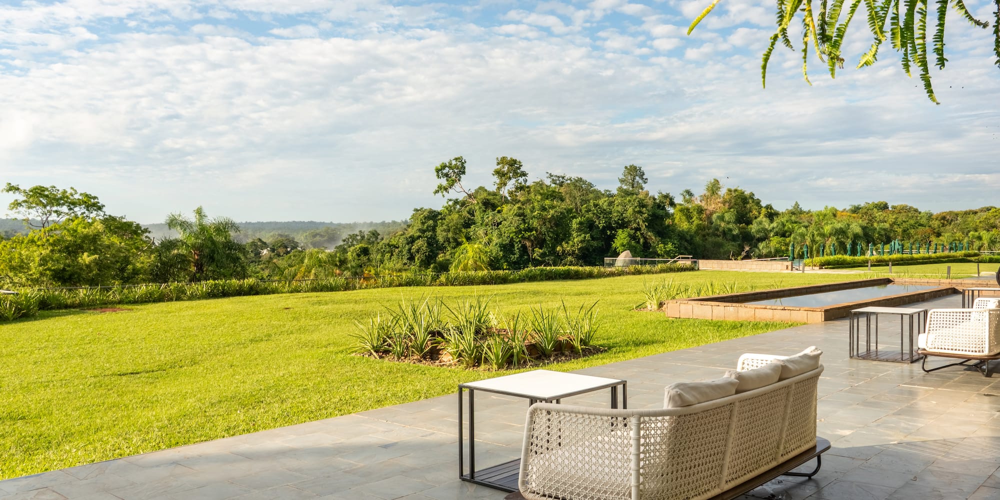 a white couch on a patio with a table and grass field