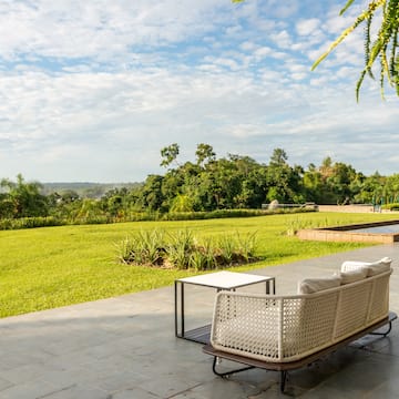 a white couch on a patio with a table and grass field