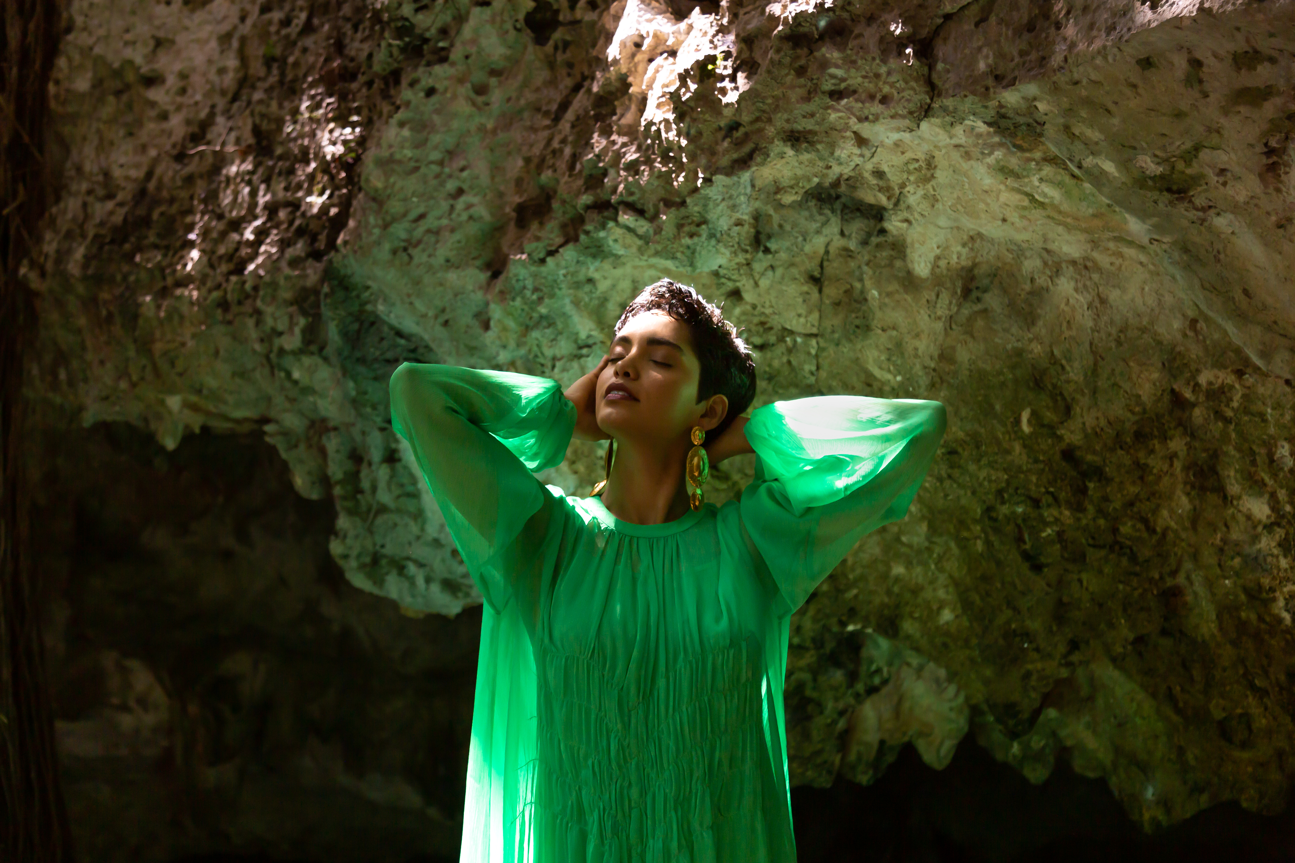a woman in a green dress with her eyes closed
