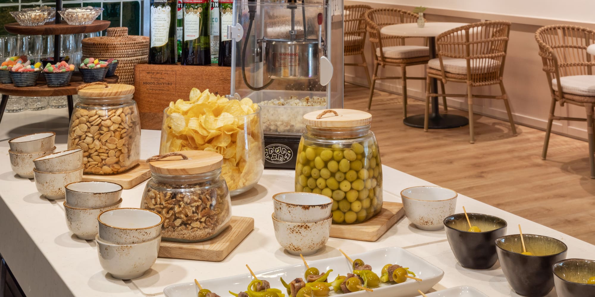 Barra de aperitivos: aceitunas, patatas fritas, frutos secos, palomitas y vermut.
