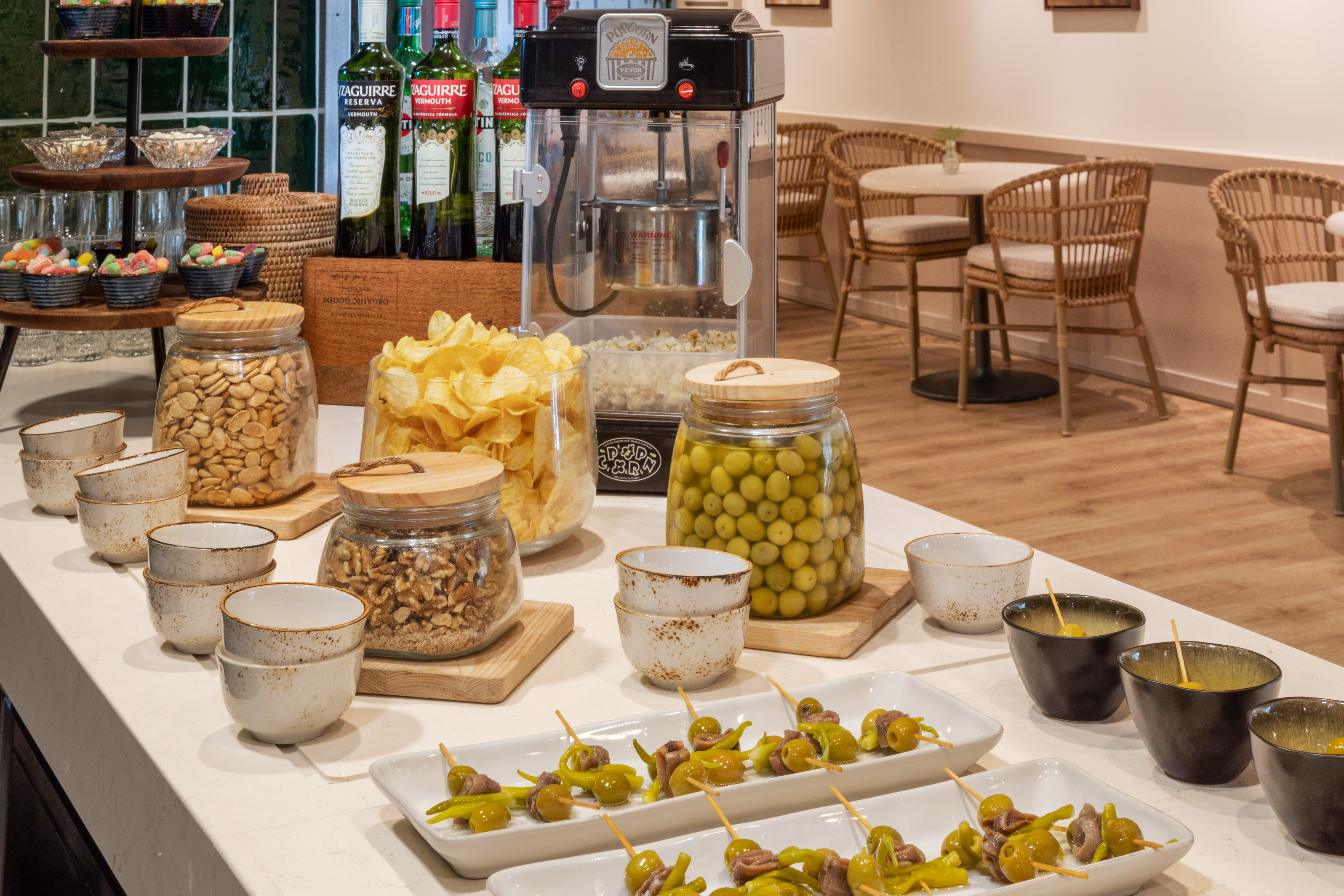 Barra de aperitivos: aceitunas, patatas fritas, frutos secos, palomitas y vermut.