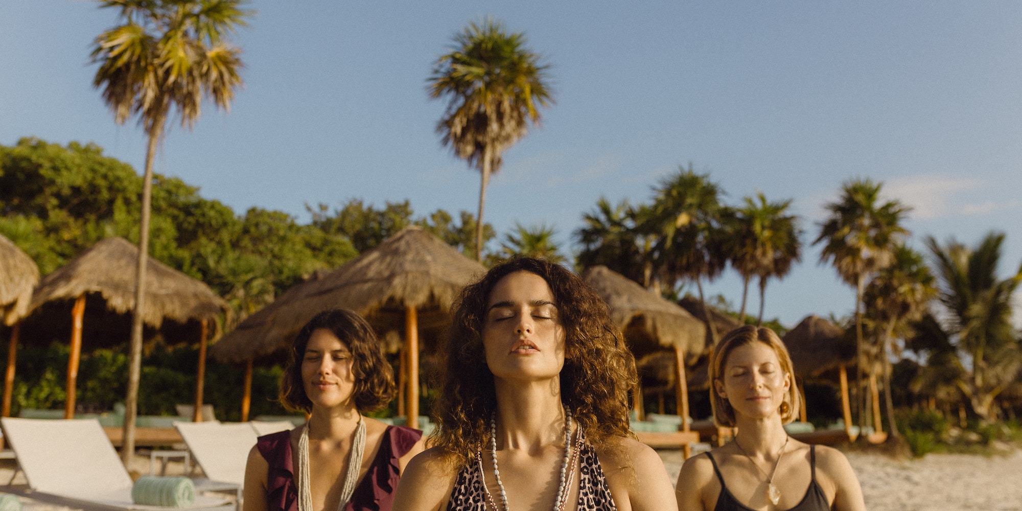 a group of women meditating on a beach