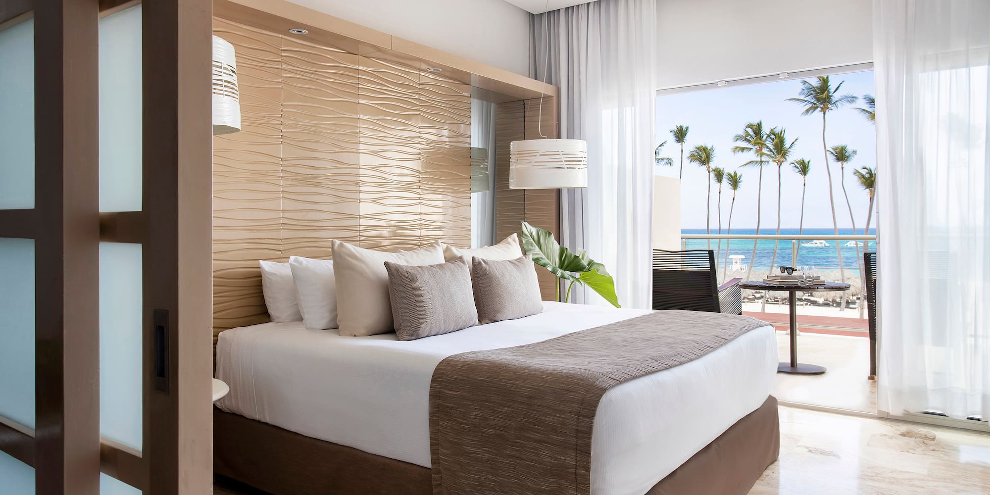 a bed with a large headboard and a large window with palm trees
