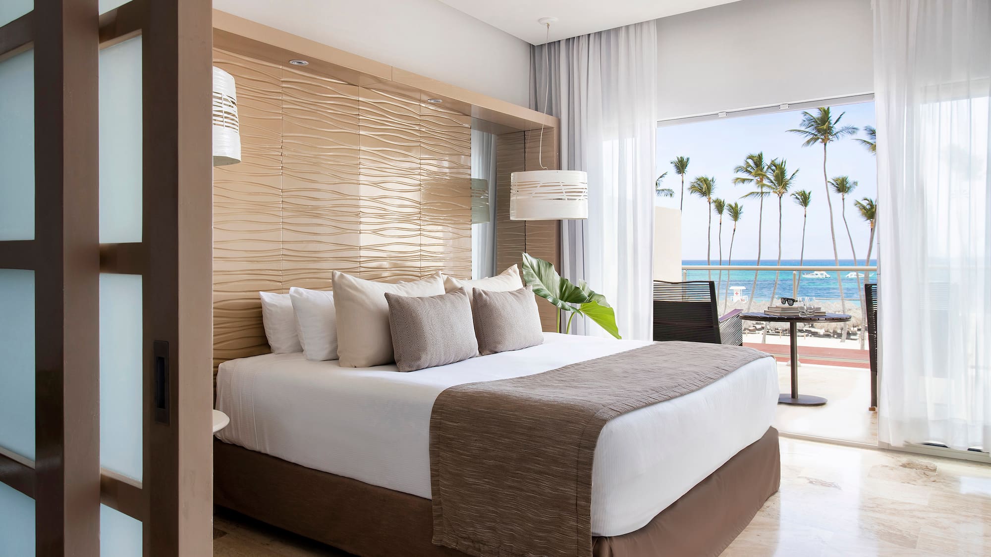 a bed with a large headboard and a large window with palm trees