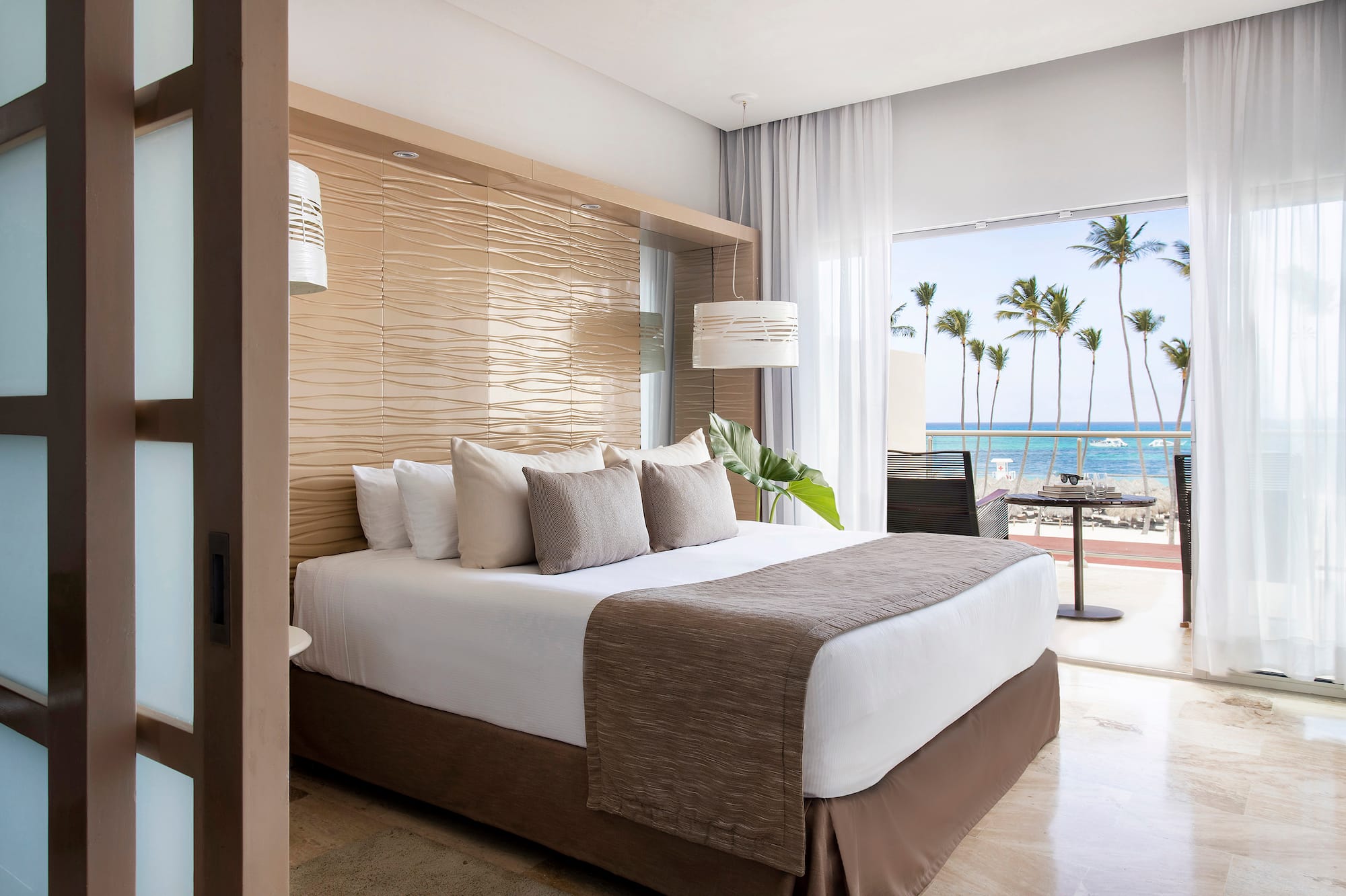 a bed with a large headboard and a large window with palm trees
