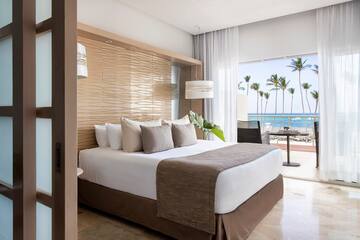 a bed with a large headboard and a large window with palm trees