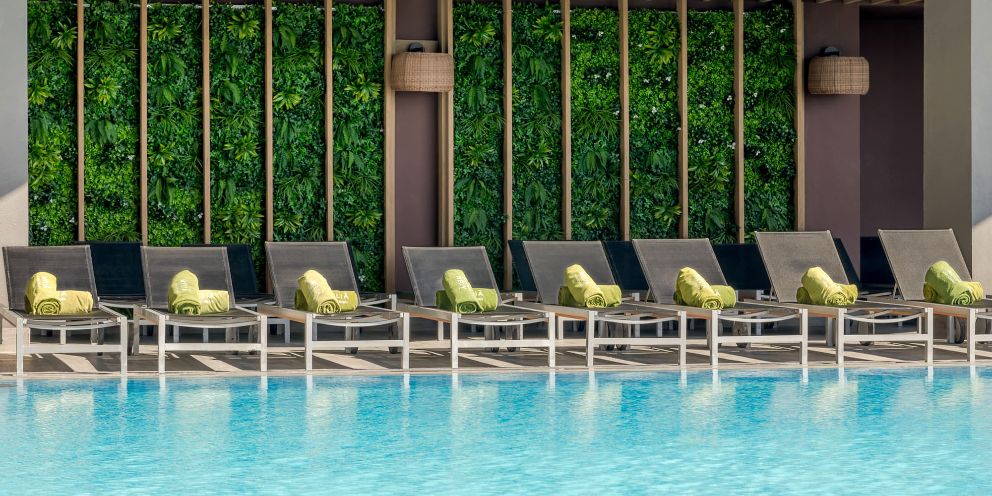 a pool with lounge chairs and a green wall