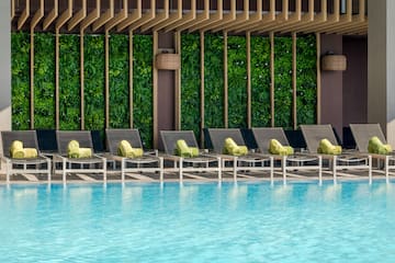 a pool with lounge chairs and a green wall