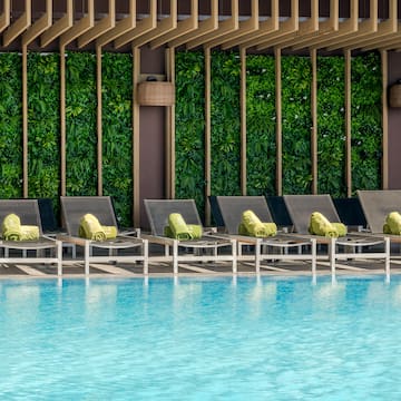 a pool with lounge chairs and a green wall