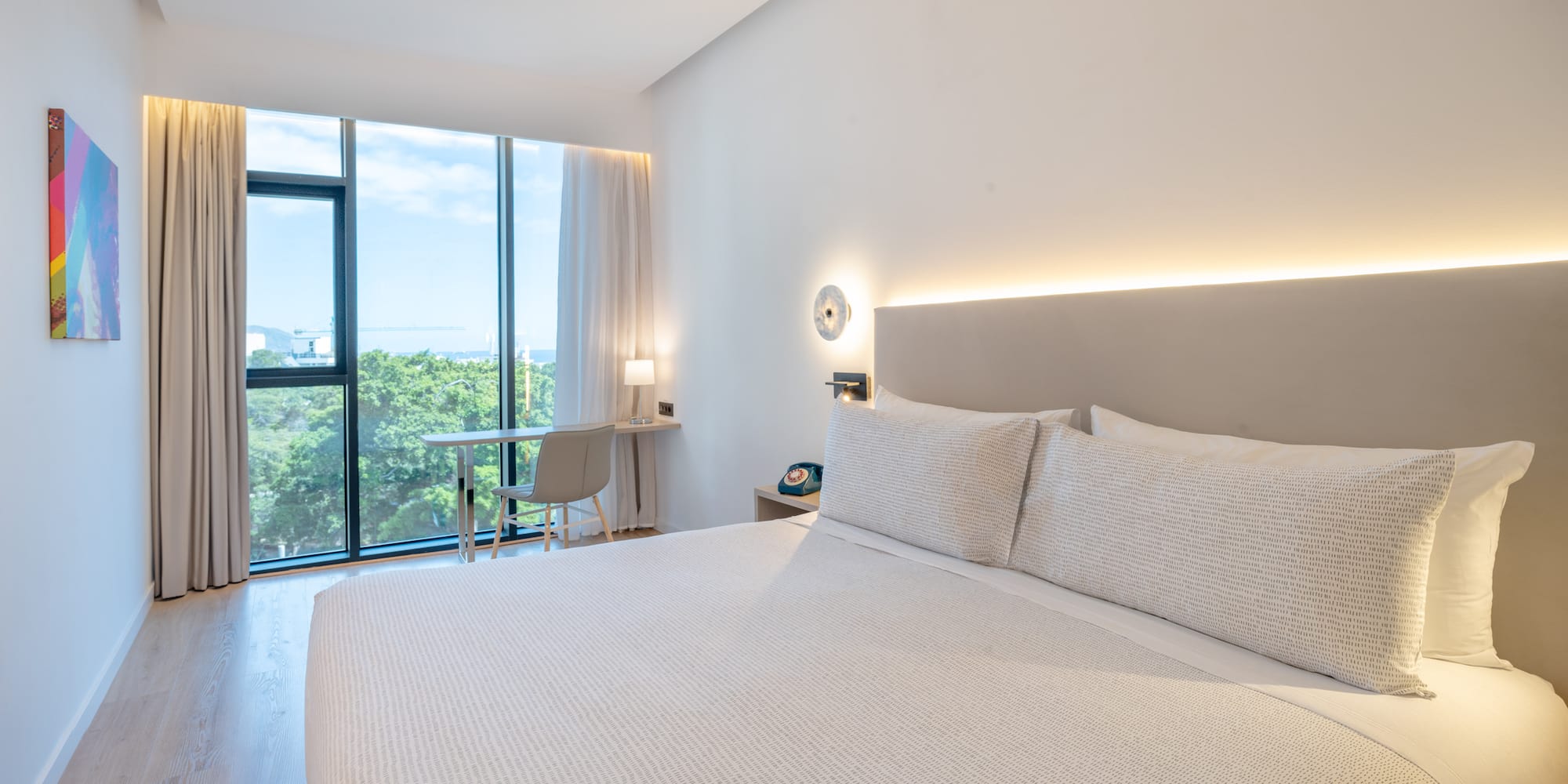 a bed with a white cover and a desk and a chair in a room with windows