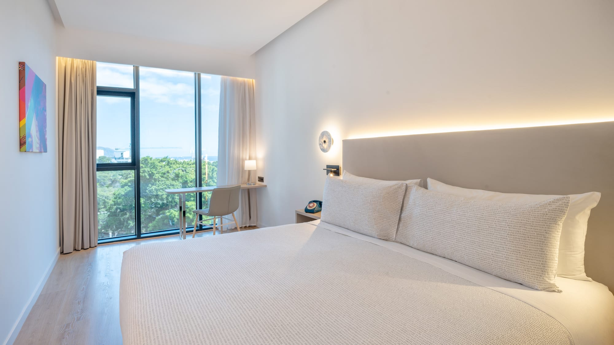 a bed with a white cover and a desk and a chair in a room with windows