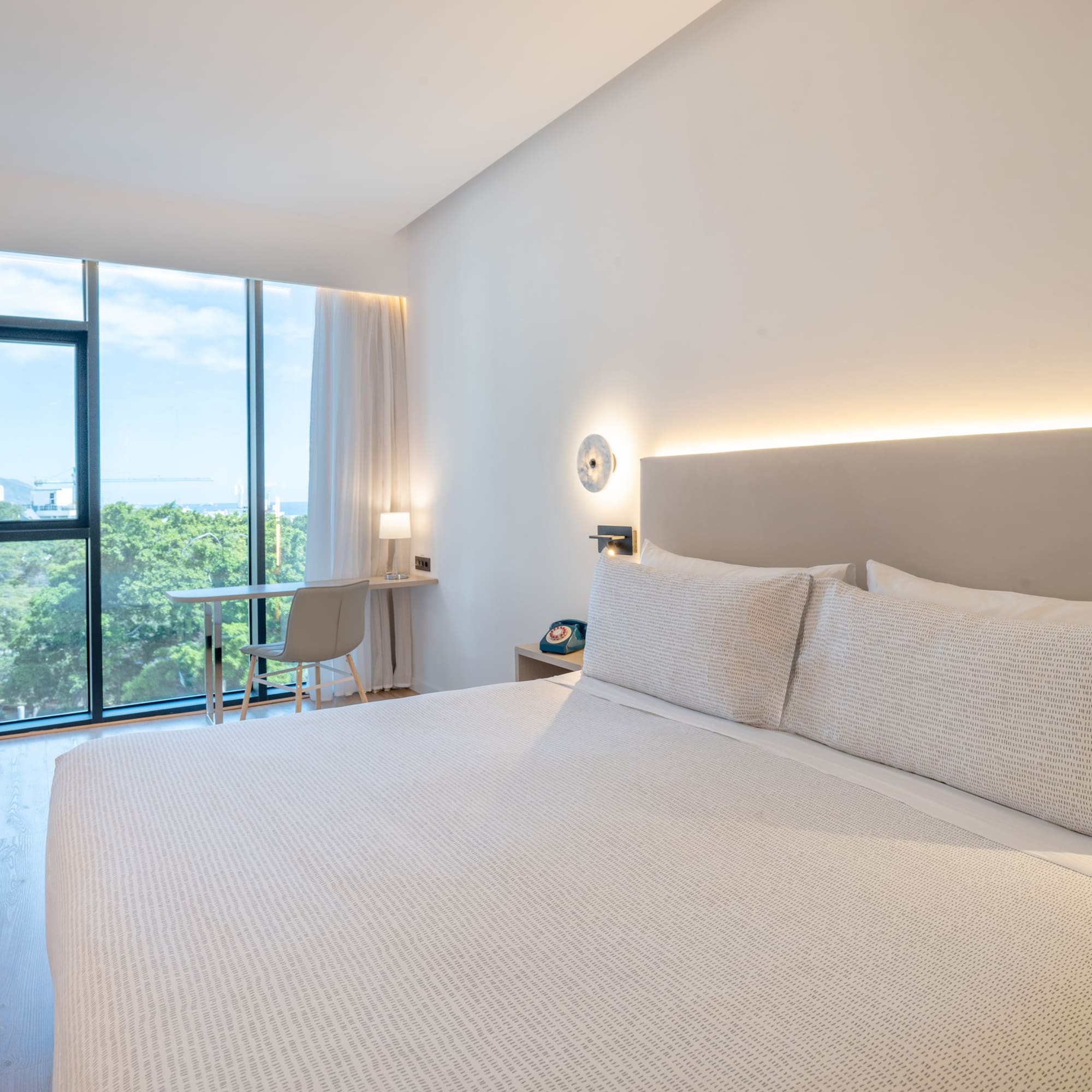 a bed with a white cover and a desk and a chair in a room with windows