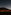 Dark car on road under vast starry night sky, large volcanic mountain in background.