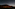 Dark car on road under vast starry night sky, large volcanic mountain in background.