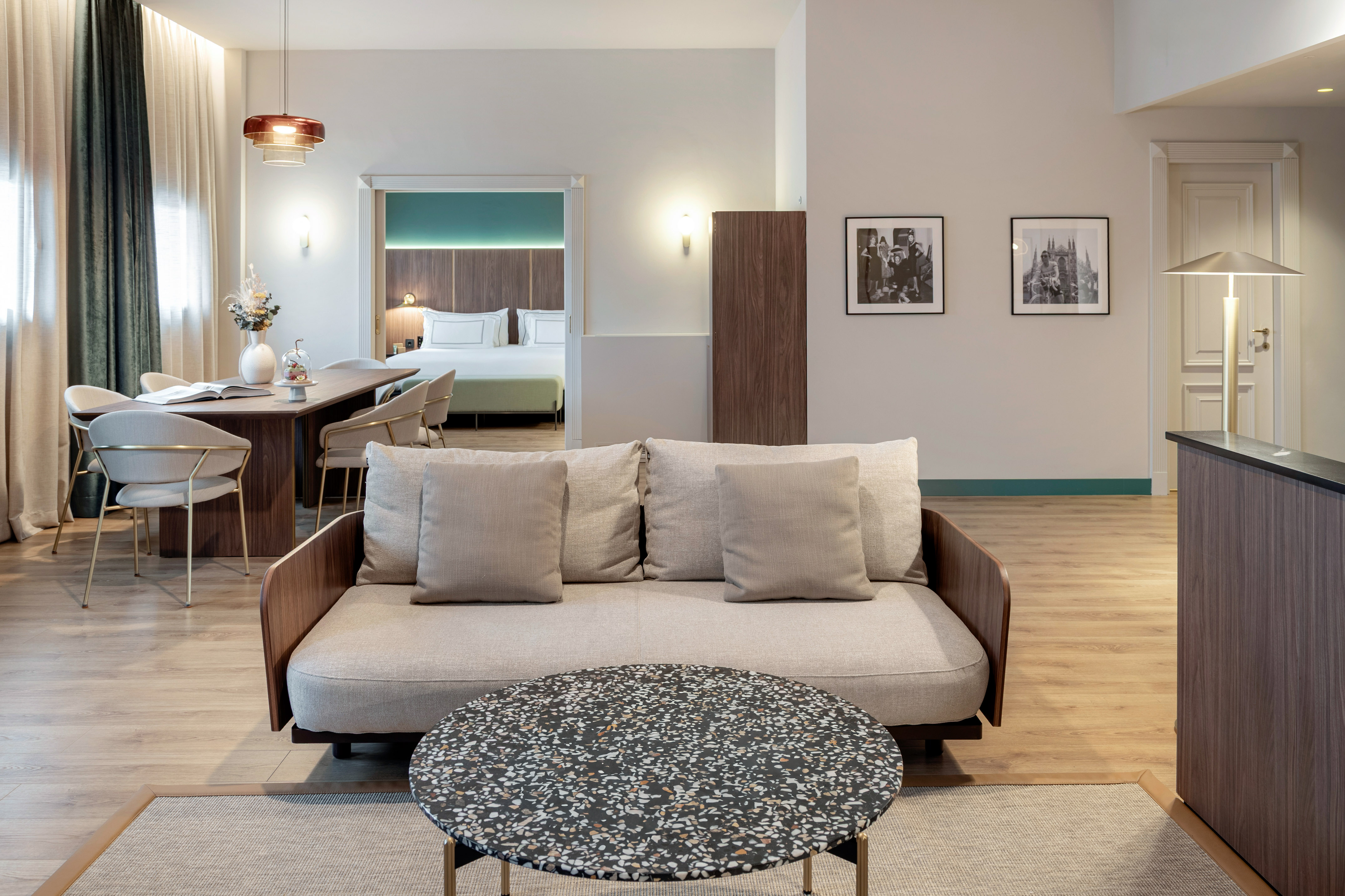 Modern hotel suite living room, dining area, and connected bedroom.